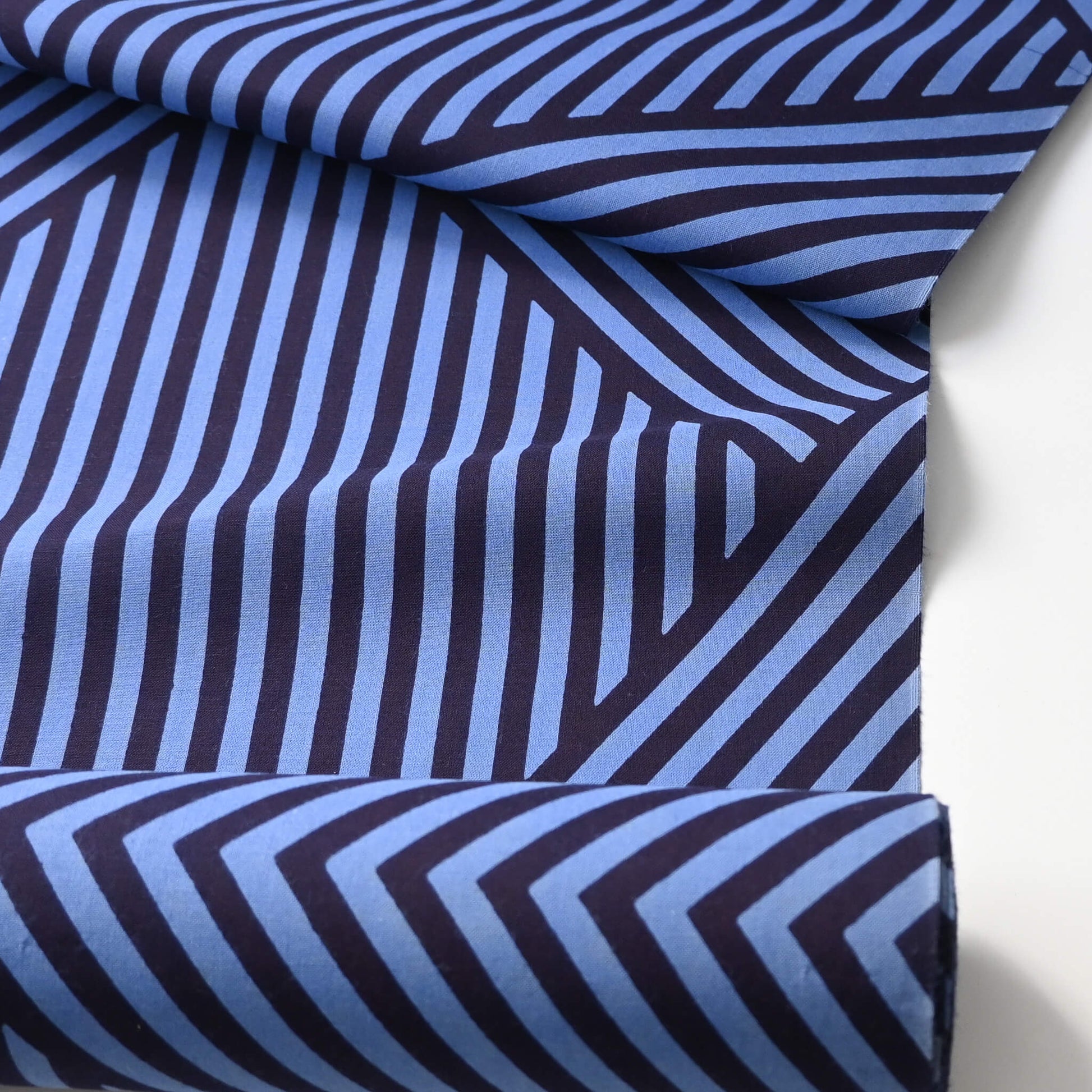 Close-up view of vintage traditional Japanese men's yukata cotton fabric with bold geometric stripe pattern in bright blue and navy.