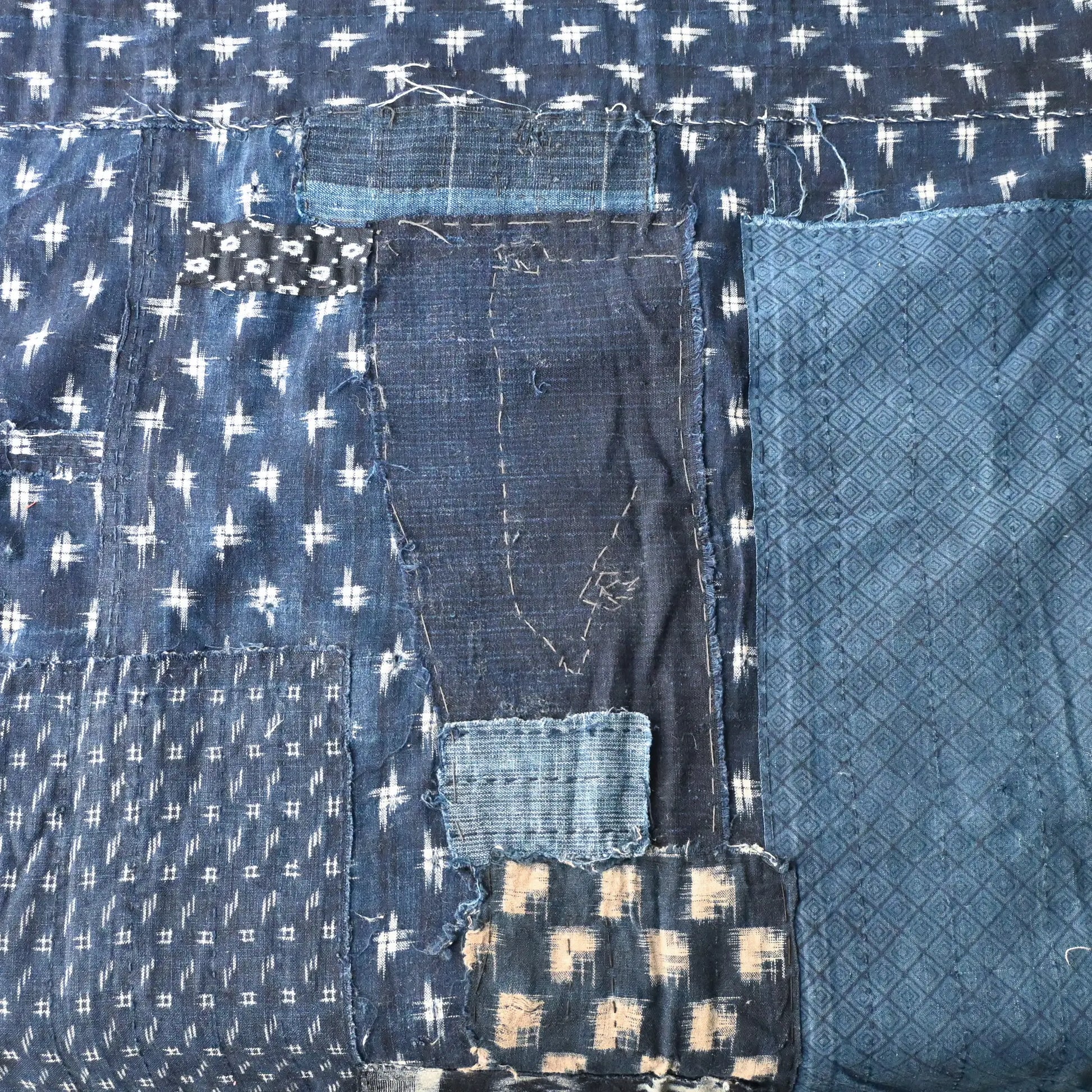 Detailed view of vintage Boro  indigo Kasuri cotton futon cover with patches and stitches.