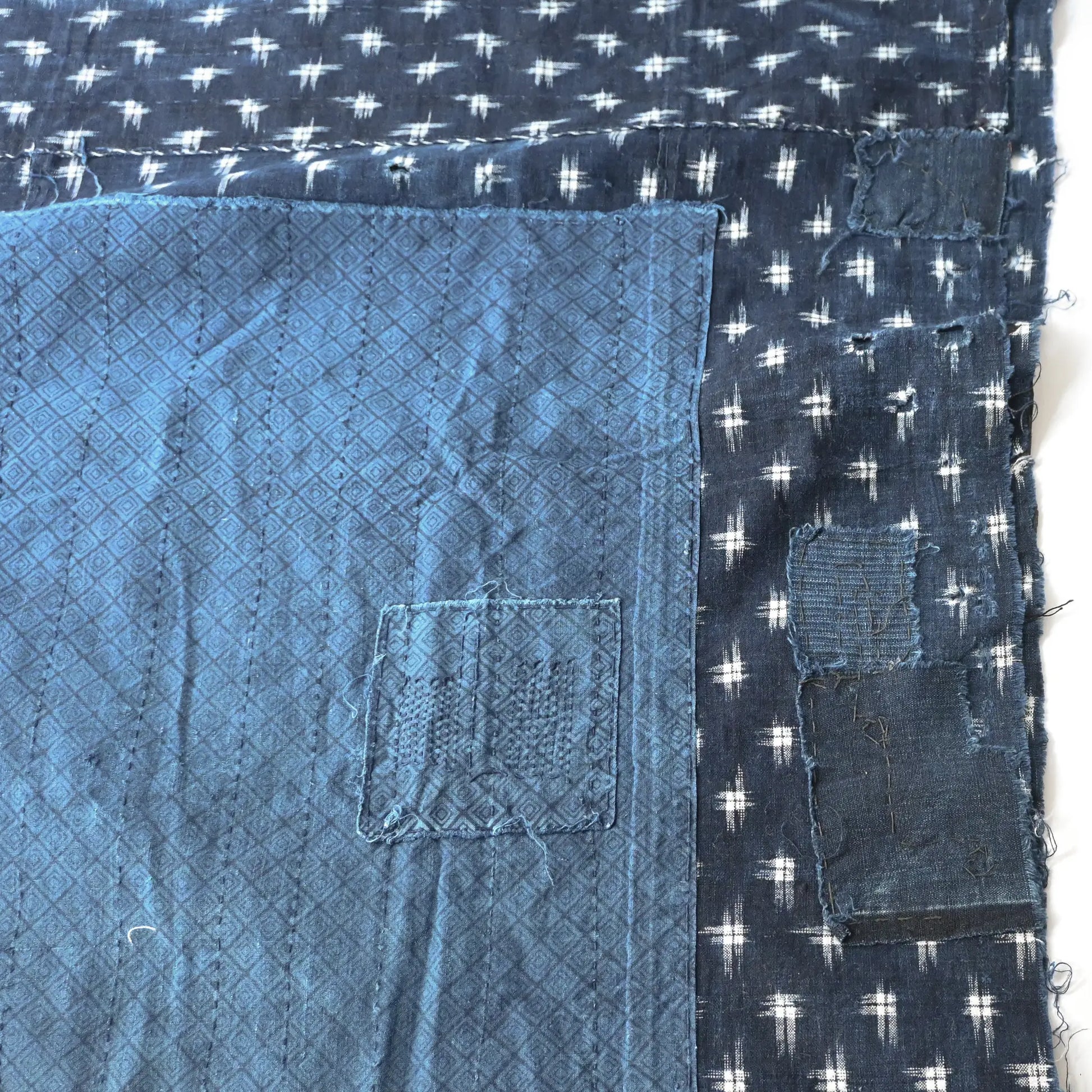 Detailed view of vintage Boro  indigo Kasuri cotton futon cover with patches and stitches.