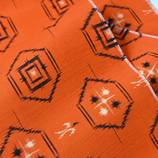 Detailed view of vintage bright tsumugi silk kimono fabric roll with black Kikko motif.