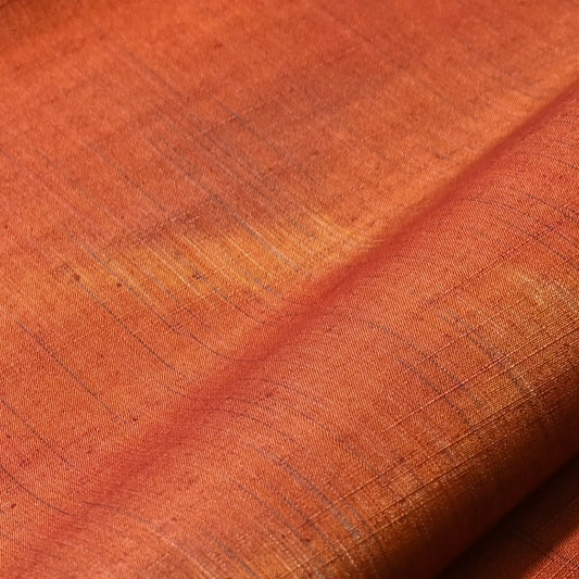 Close-up view of vintage burnt orange tsumugi silk kimono fabric roll sold by the metre.
