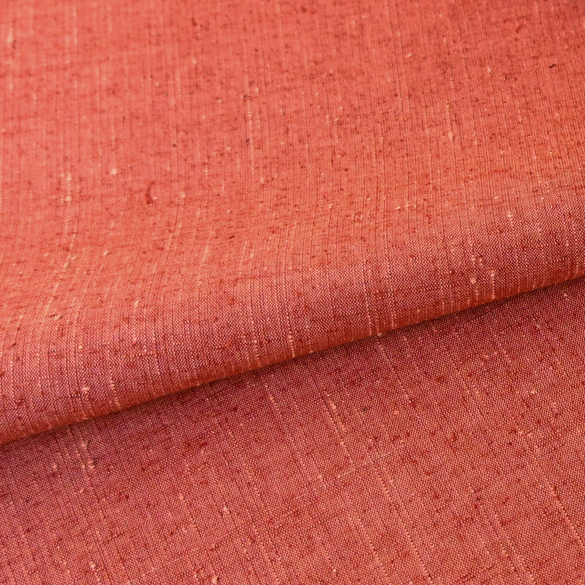 Close-uo view of vintage warm coral orange tsumugi silk kimono fabric with slubs, sold by the metre.