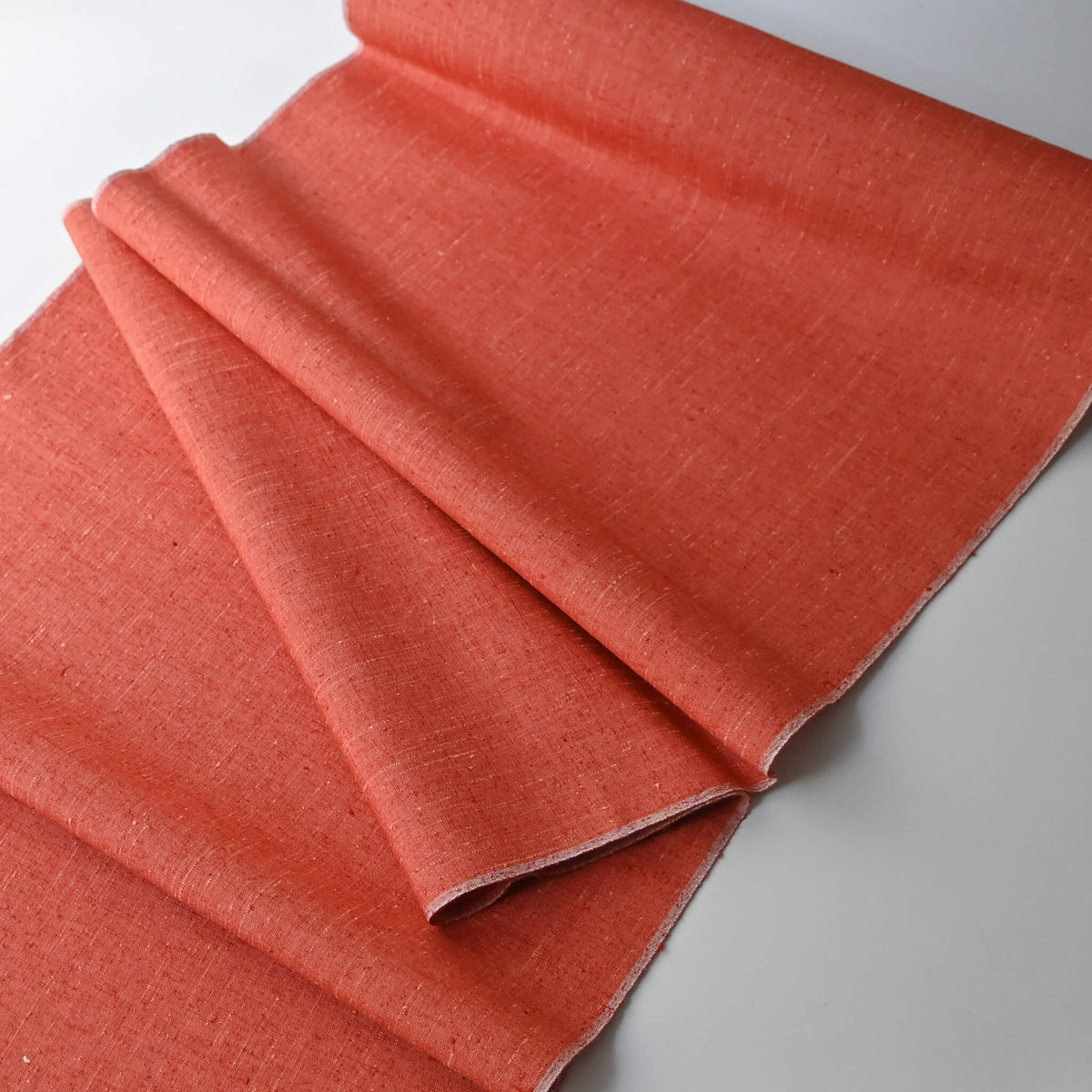 Full view of vintage warm coral orange tsumugi silk kimono fabric with slubs, sold by the metre.