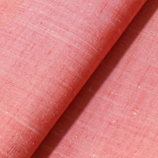 Detailed view of vintage plain tsumugi silk kimono fabric roll in coral pink with natural slubs from the late 20th C.