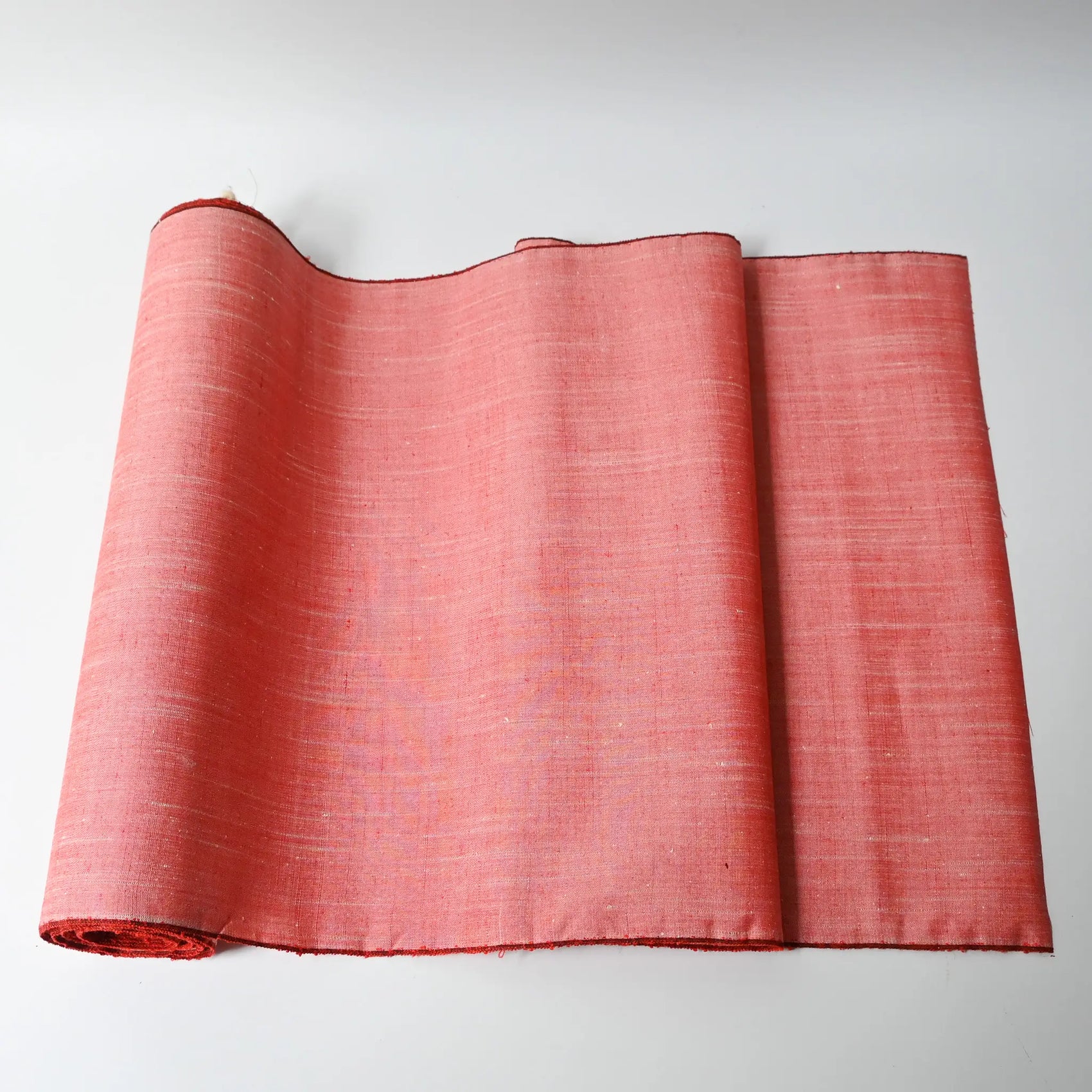 Vintage plain tsumugi silk kimono fabric roll in coral pink with natural slubs from the late 20th C.
