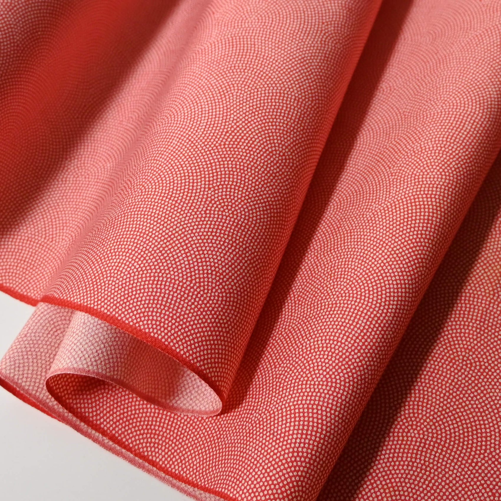 Close-up view of vintage edokomon kimono silk fabric in red coral with seigaiha wave pattern sold by the metre.