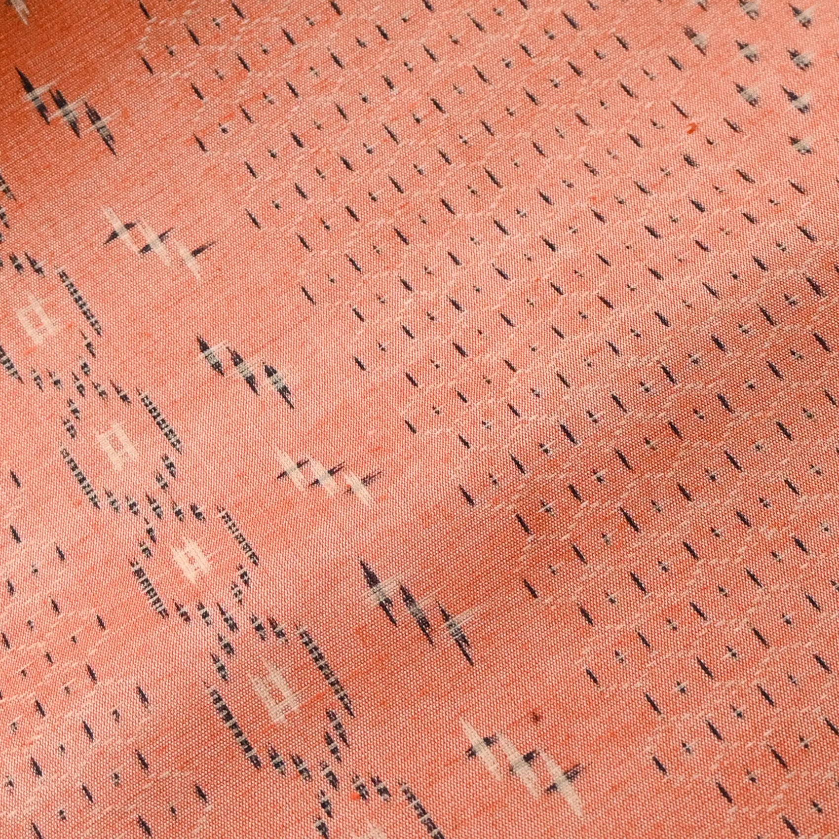 Close-up view of vintage coral tsumugi kimono silk with kasuri tortoiseshell Kikko pattern, sold by the metre.