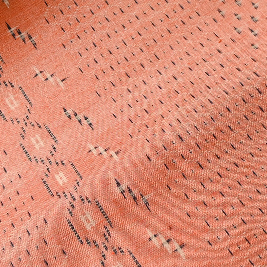 Close-up view of vintage coral tsumugi kimono silk with kasuri tortoiseshell Kikko pattern, sold by the metre.