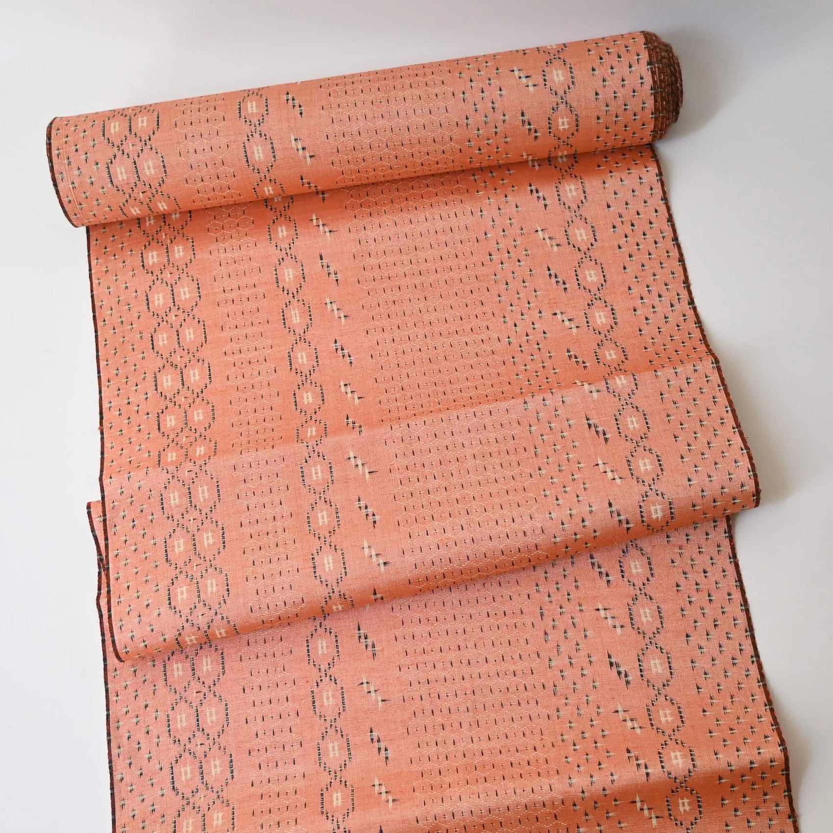 Full view of vintage coral tsumugi kimono silk with kasuri tortoiseshell Kikko pattern, sold by the metre.