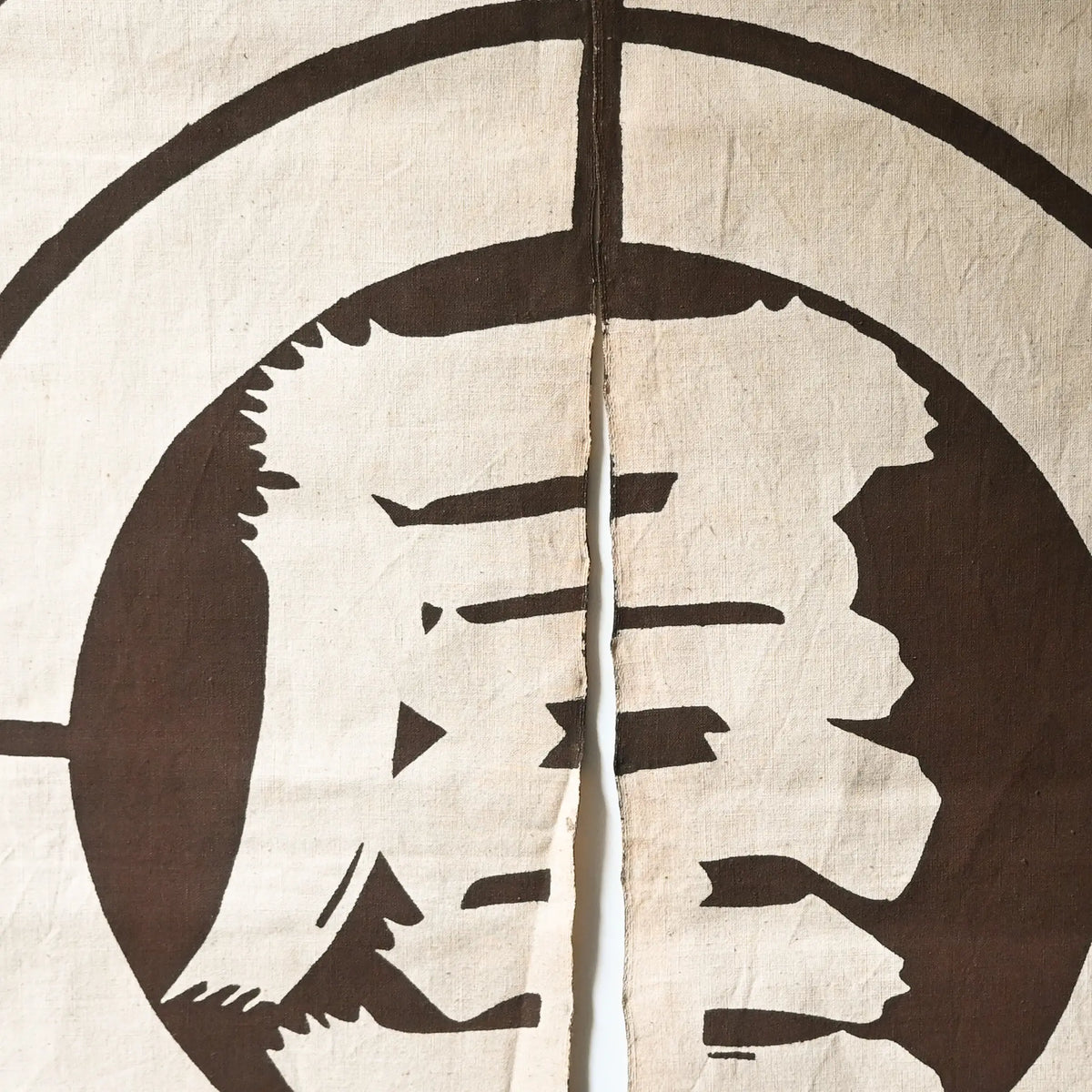 Close-up view of vintage four-panel brown cotton shop noren with a bold logo from mid-20th Century.
