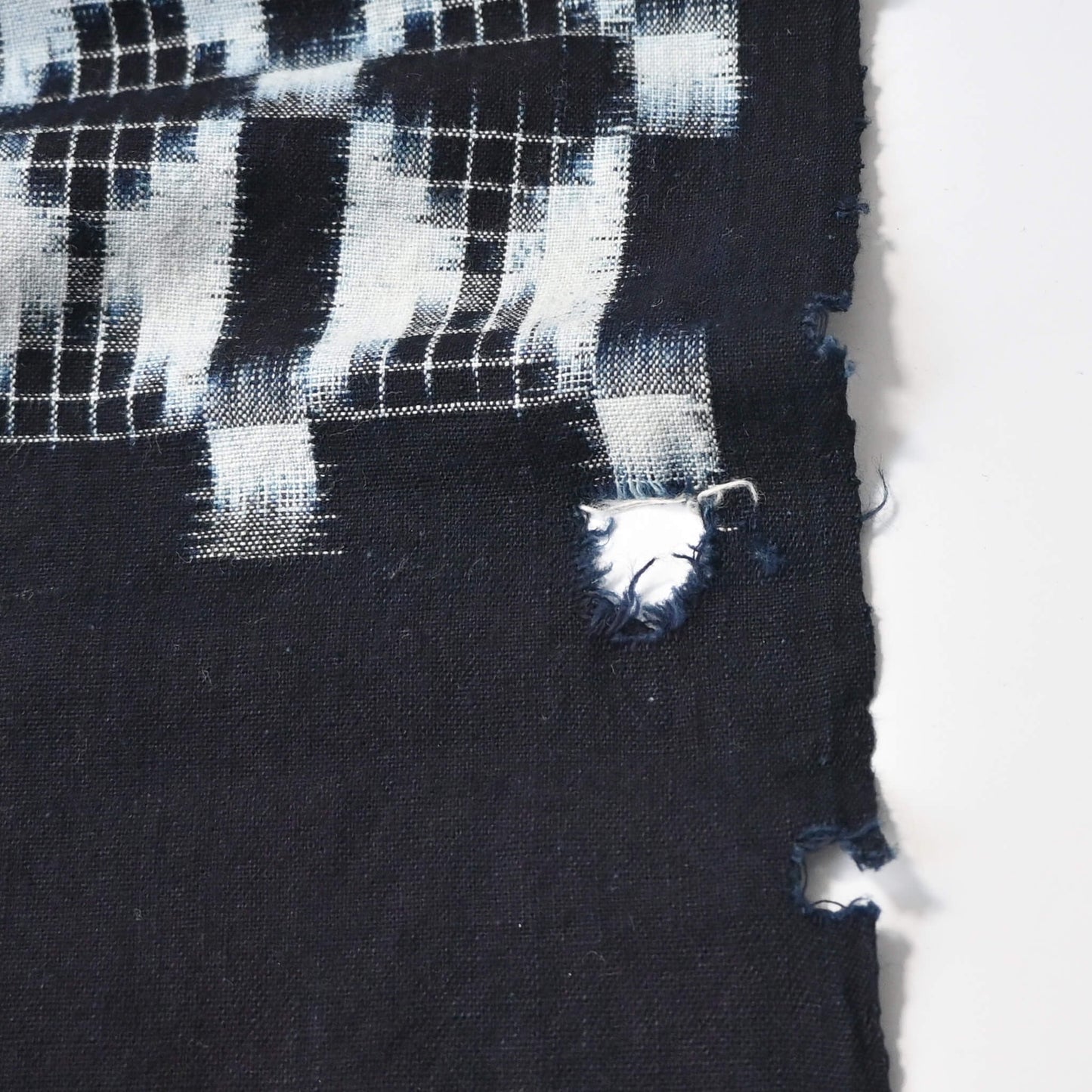 Detailed view of vintage four-panel indigo egasuri cotton futon cover, some holes.