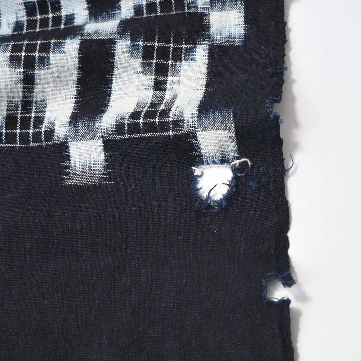 Detailed view of vintage four-panel indigo egasuri cotton futon cover, some holes.