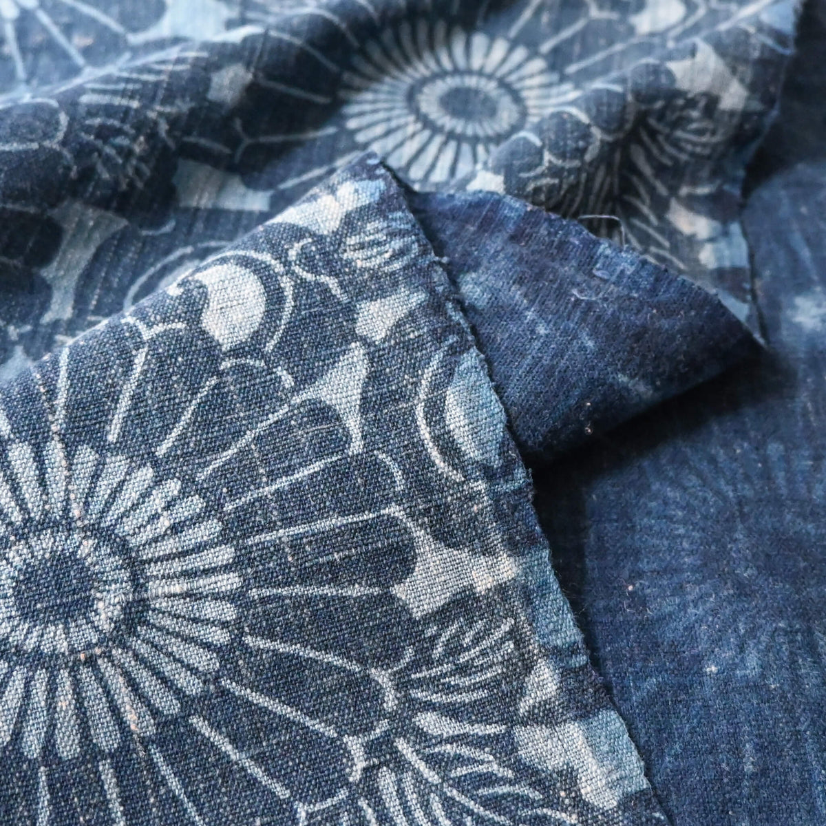 Close-up view of vintage four-panel indigo katazome dyed cotton futon cover with chrysanthemum arabesque motif.