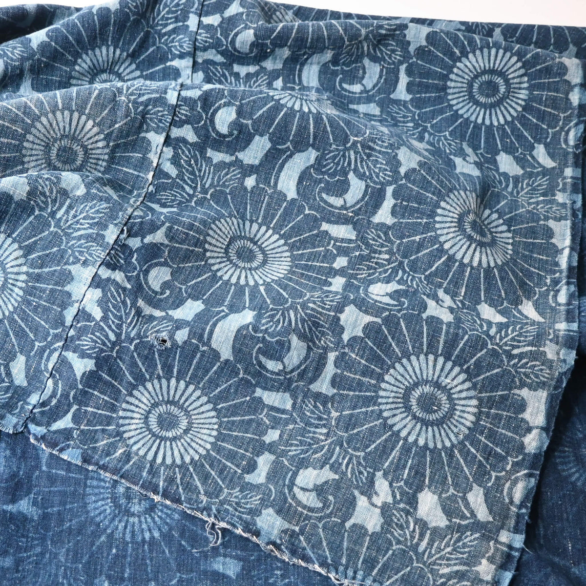 Close-up view of vintage four-panel indigo katazome dyed cotton futon cover with chrysanthemum arabesque motif.