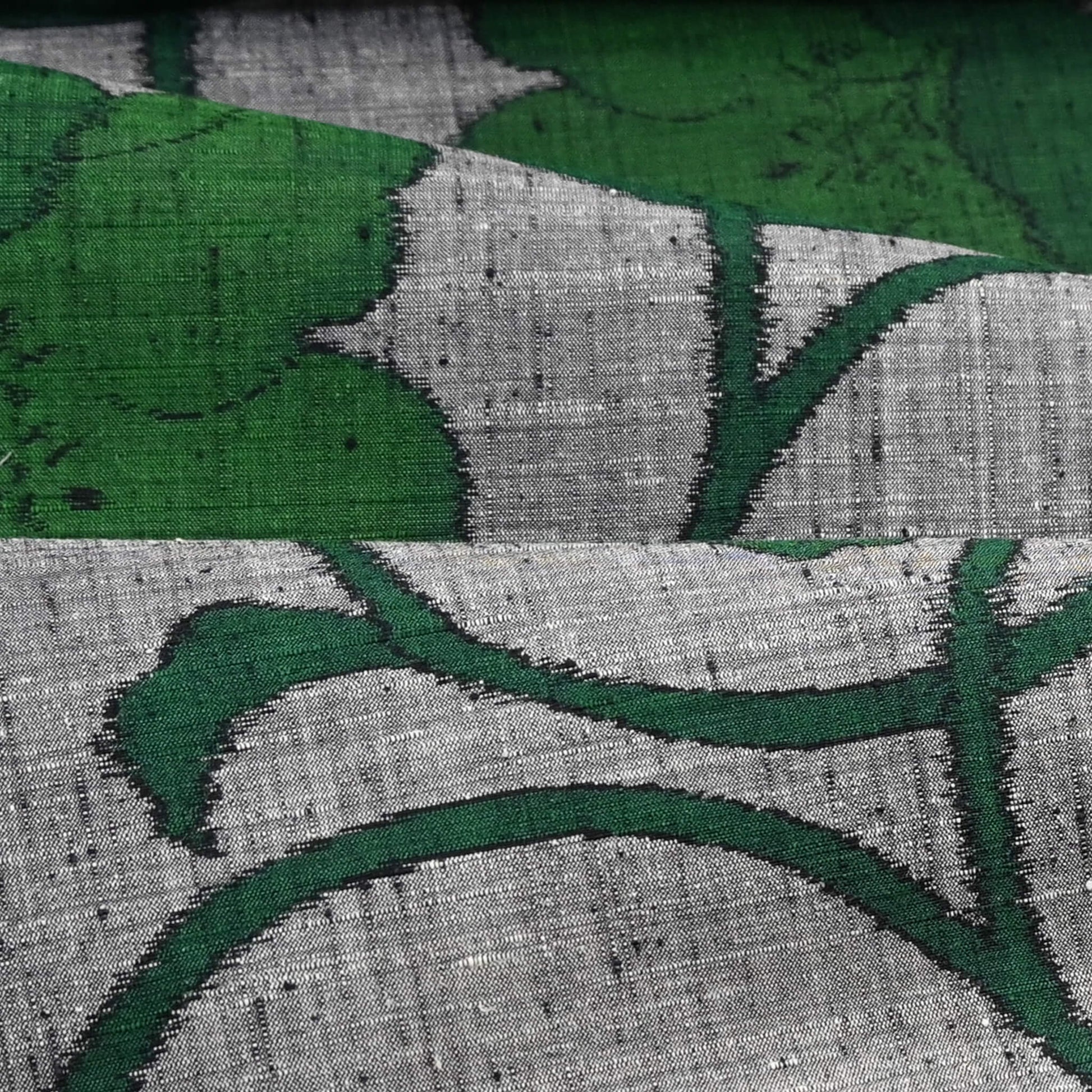 Close-up view of vintage Japanese grey tsumugi silk kimono fabric with deep green large-scale floral design.