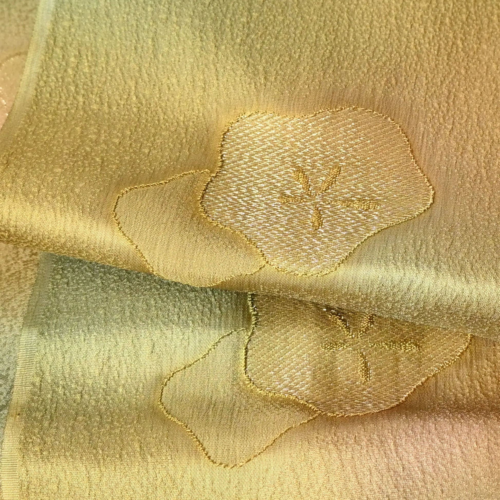 Close-up view of recycled green silk obiage with gold plum blossom.