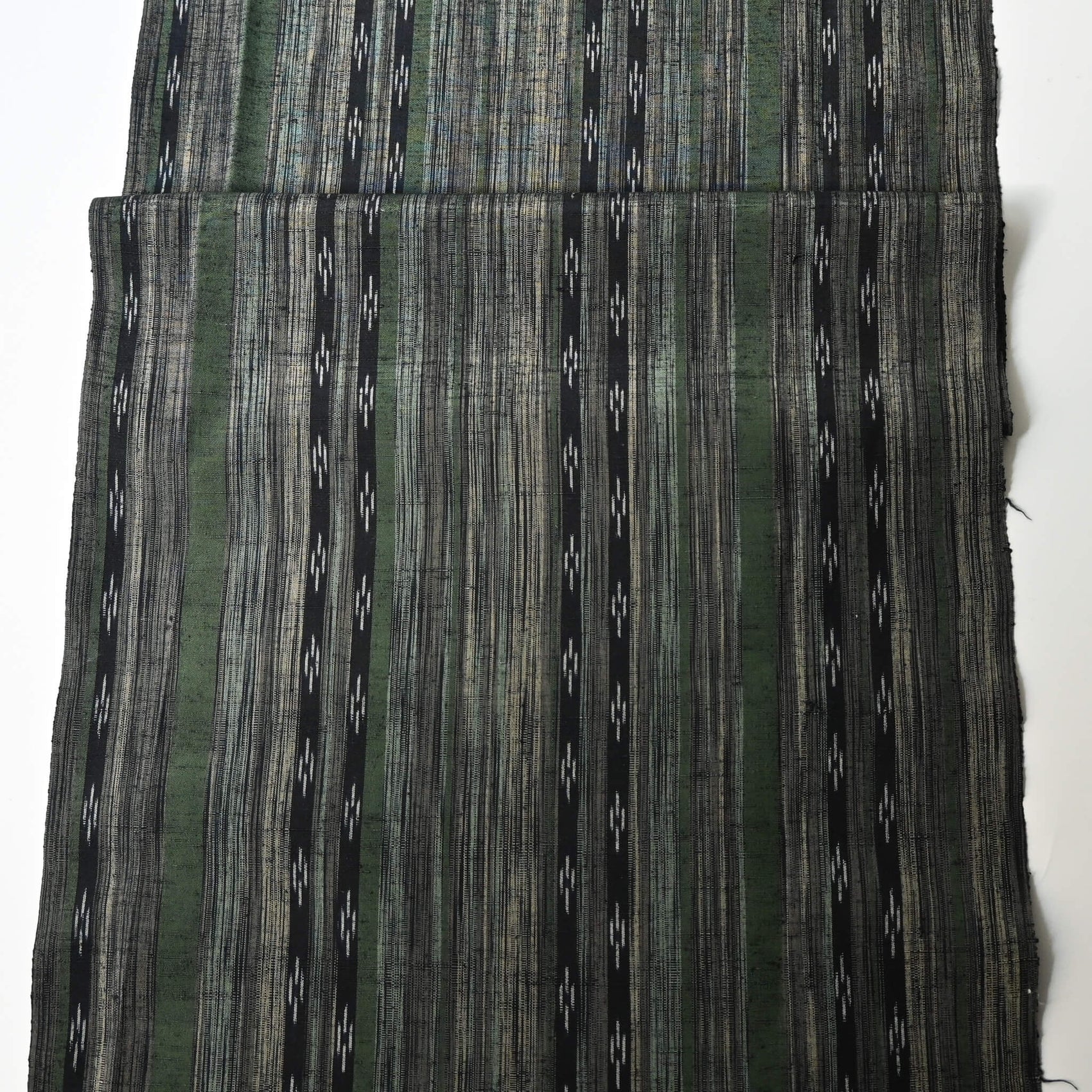 Full view of vintage tsumugi silk kimono fabric with olive green, charcoal and black stripes, and kasuri accents.