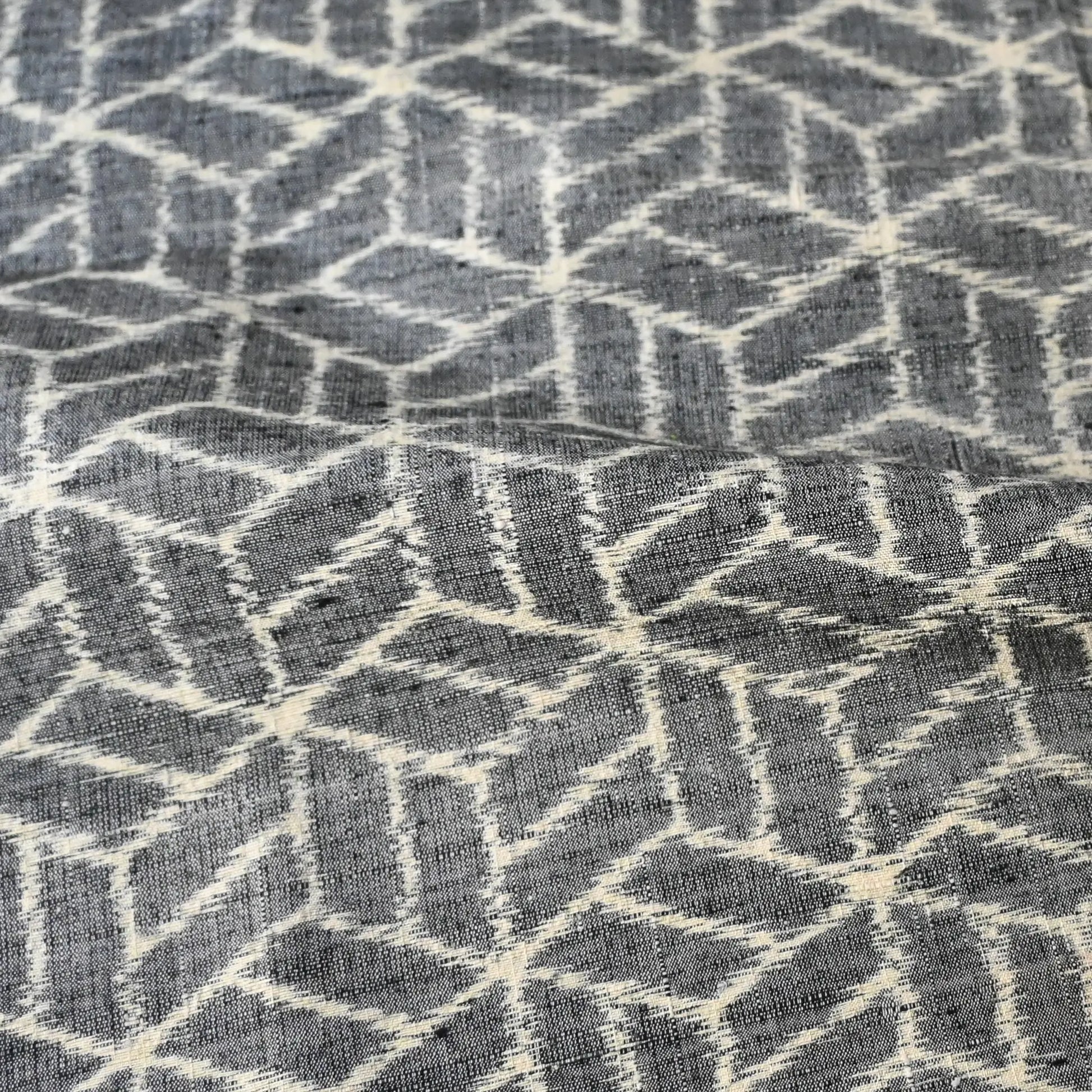 Close-up view of vintage grey tsumugi kimono silk with geometric pattern.