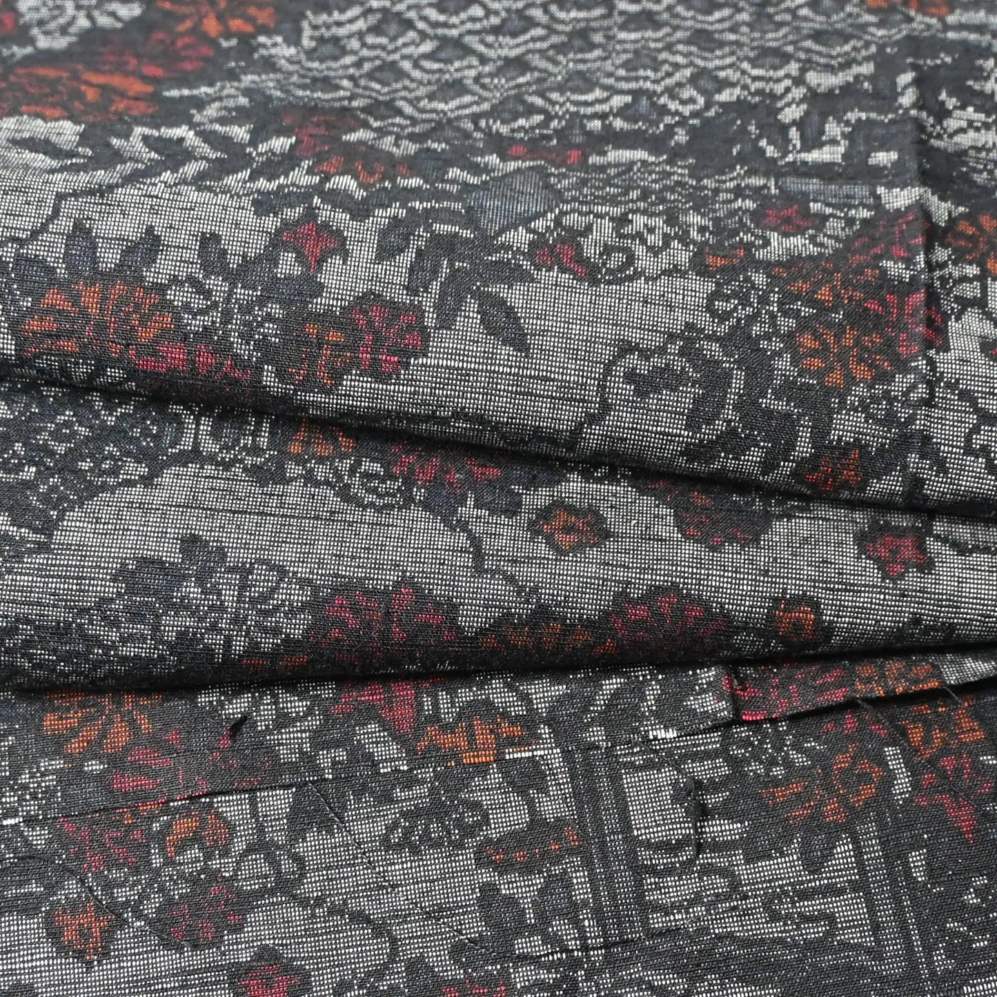 Detailed view of vintage grey tsumugi silk kimono fabric, garden with flower design.