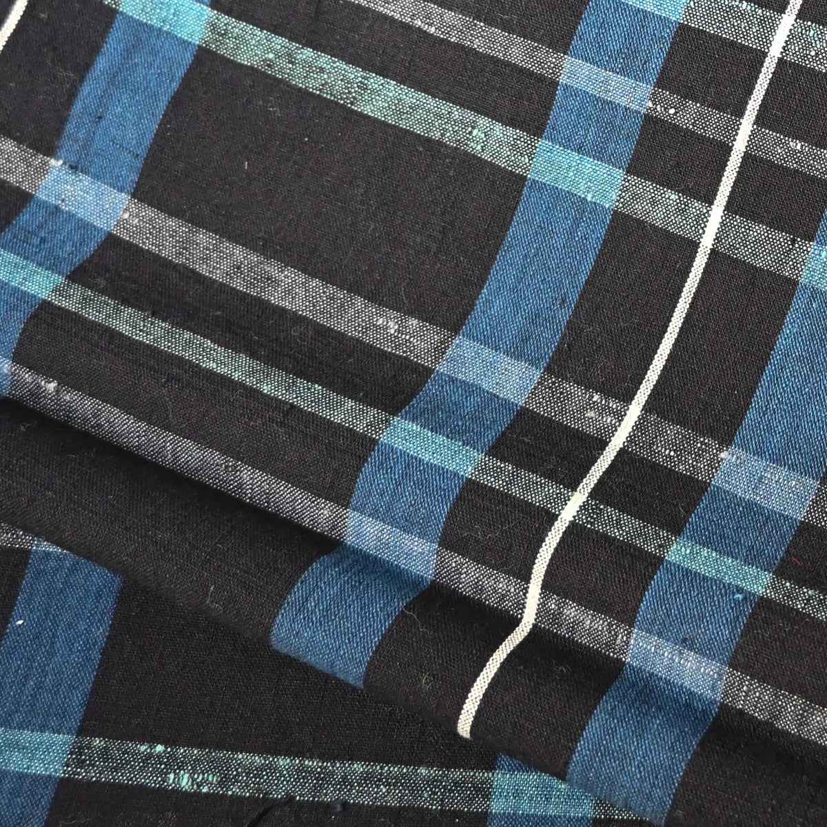 Close-up view of vintage zanshi-ori cotton fabric from a futon cover, a classic check pattern in indigo, mint green , and soft pink tones, with natural slubs.