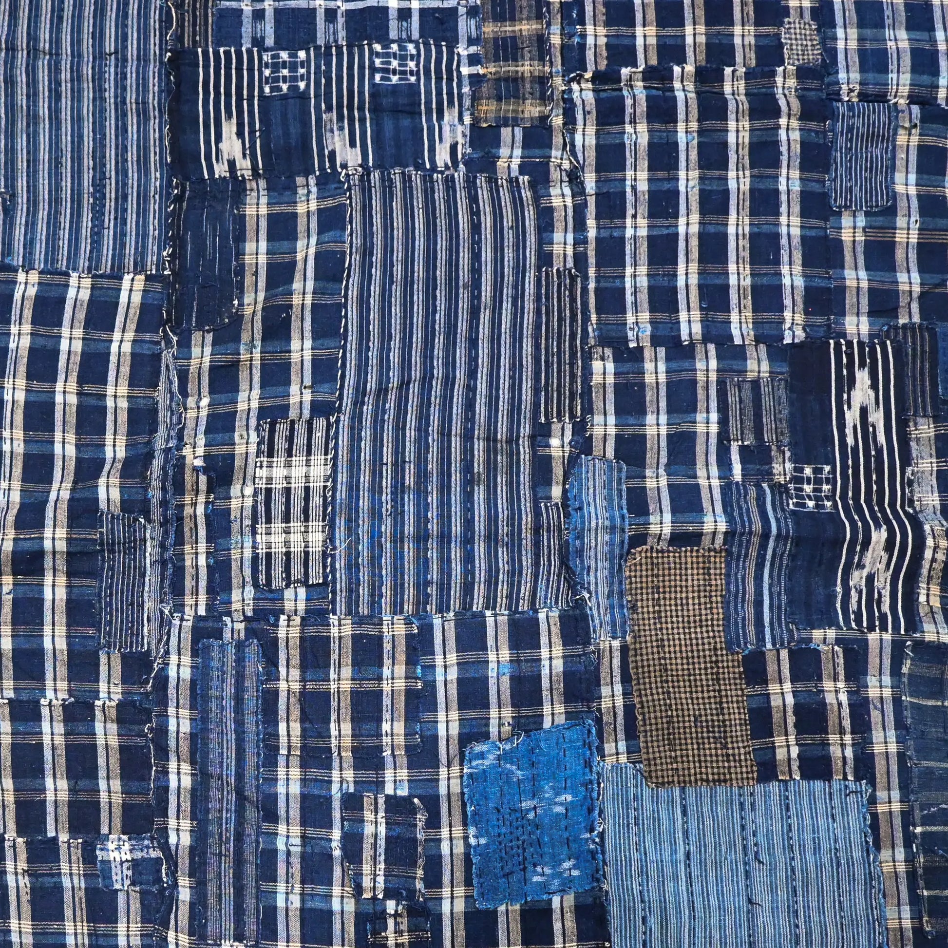 Detailed view of vintage Japanese indigo check cotton Boro futon cover with layers of mending.