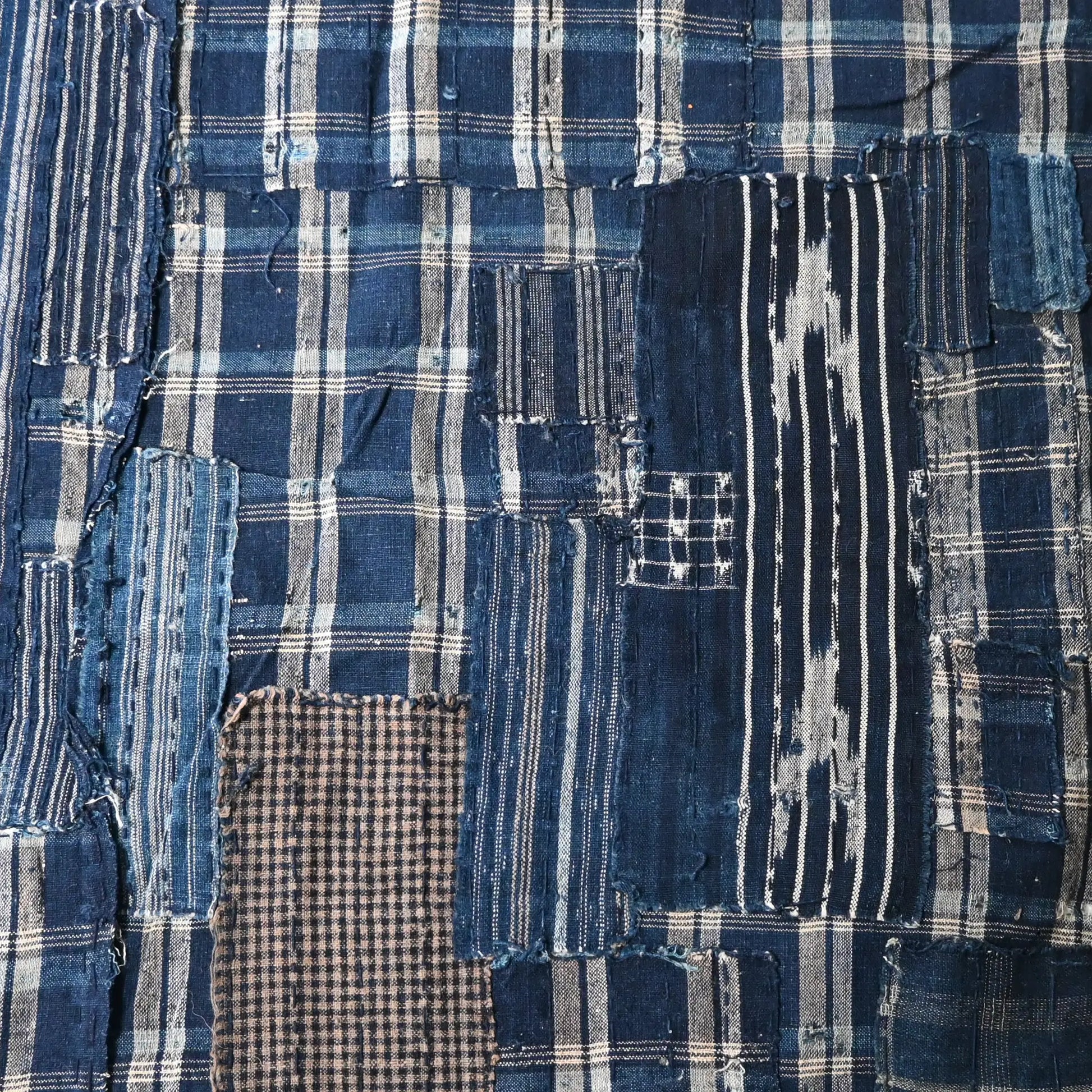 Detailed view of vintage Japanese indigo check cotton Boro futon cover with layers of mending.