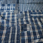 Detailed view of vintage Japanese indigo check cotton Boro futon cover with layers of mending.