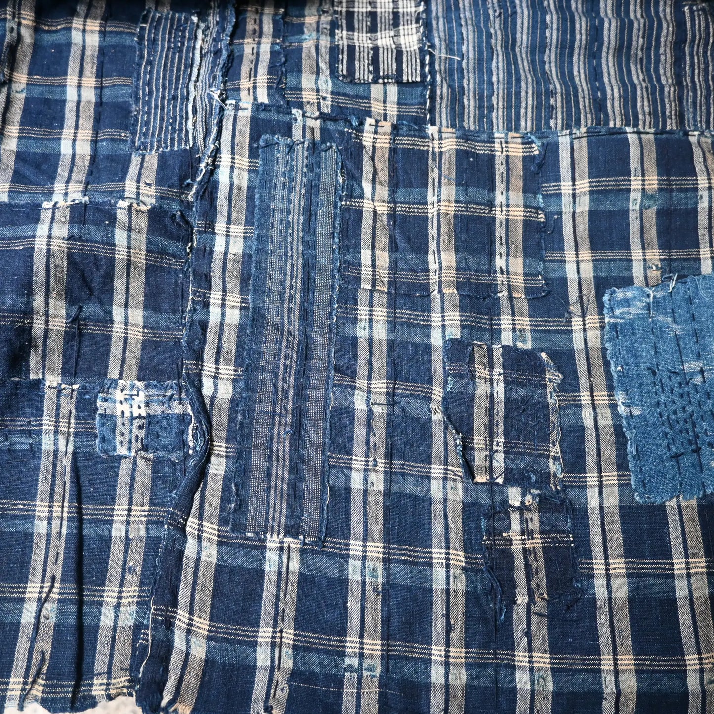 Detailed view of vintage Japanese indigo check cotton Boro futon cover with layers of mending.