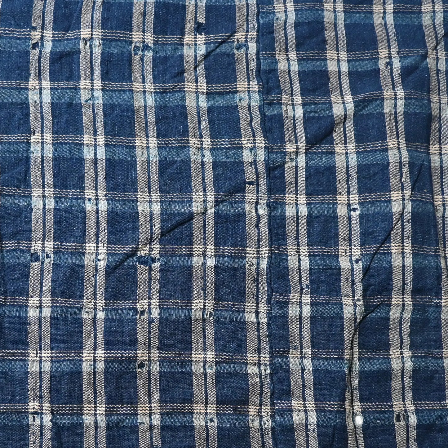 Detailed view of vintage Japanese indigo check cotton Boro futon cover with layers of mending.