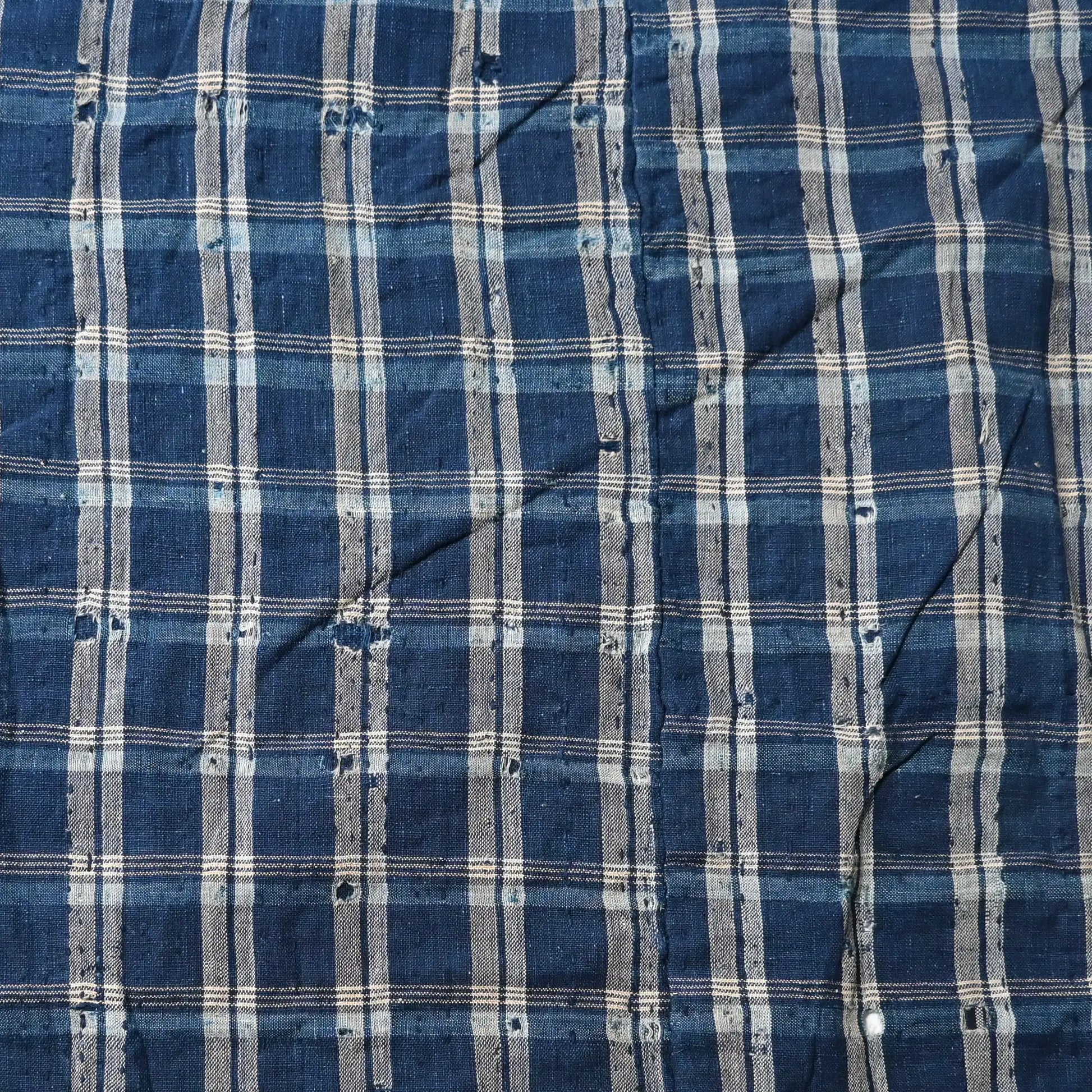 Detailed view of vintage Japanese indigo check cotton Boro futon cover with layers of mending.