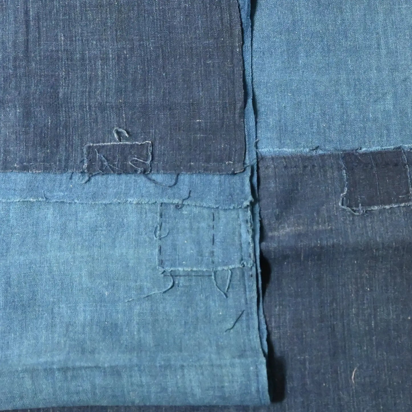 Close-up view of two fragments of vintage indigo cotton kimono lining with charming hand-stitched mends.