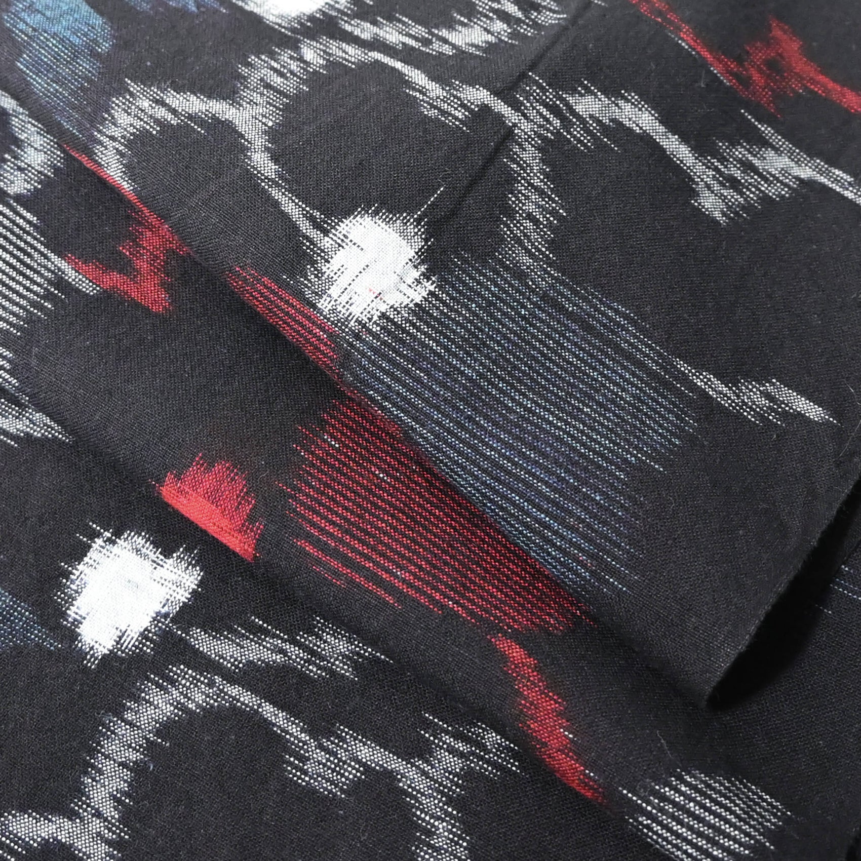 Close-up view of vintage indigo kasuri cotton kimono fabric with bold floral pattern in red and blue.
