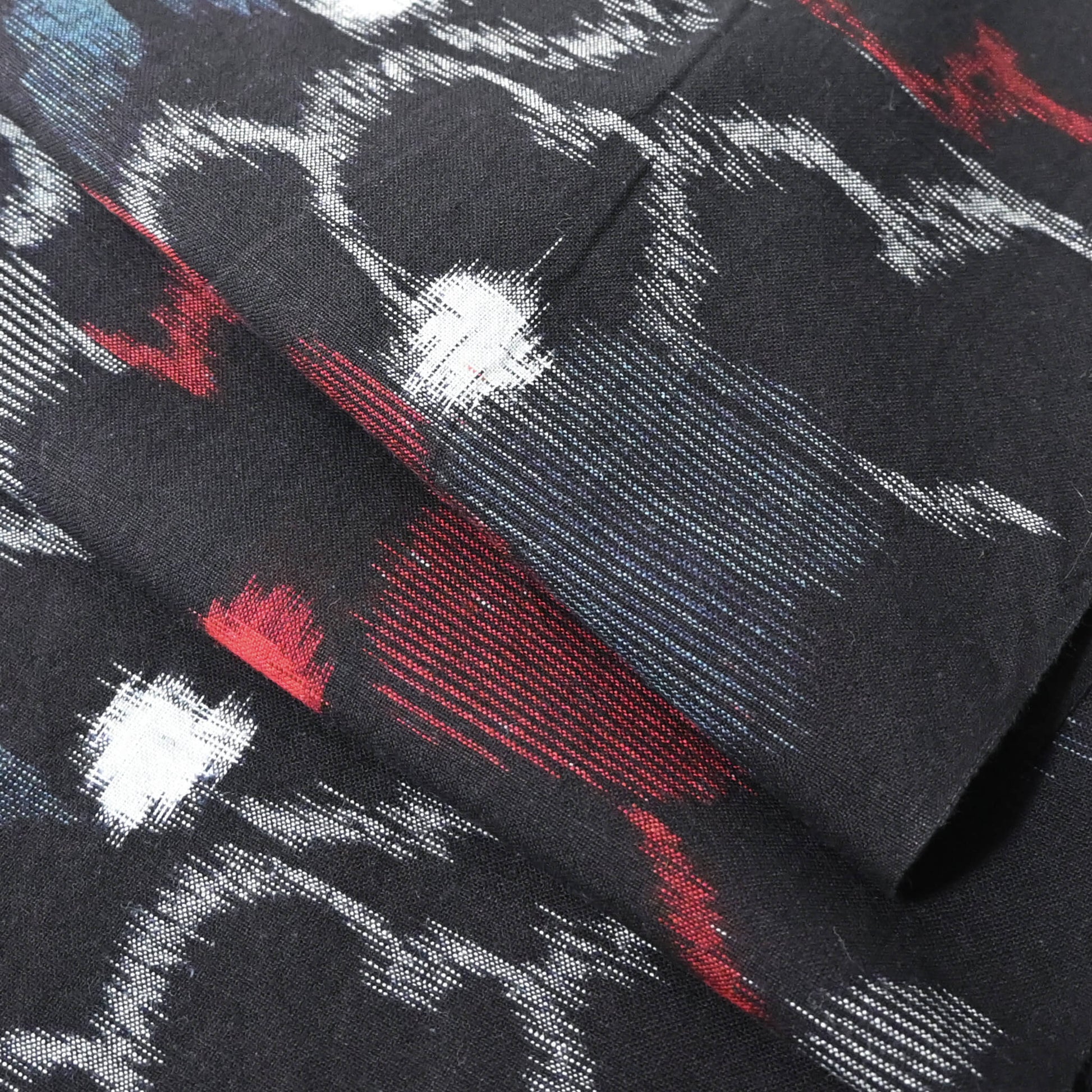 Close-up view of vintage indigo kasuri cotton kimono fabric with bold floral pattern in red and blue.