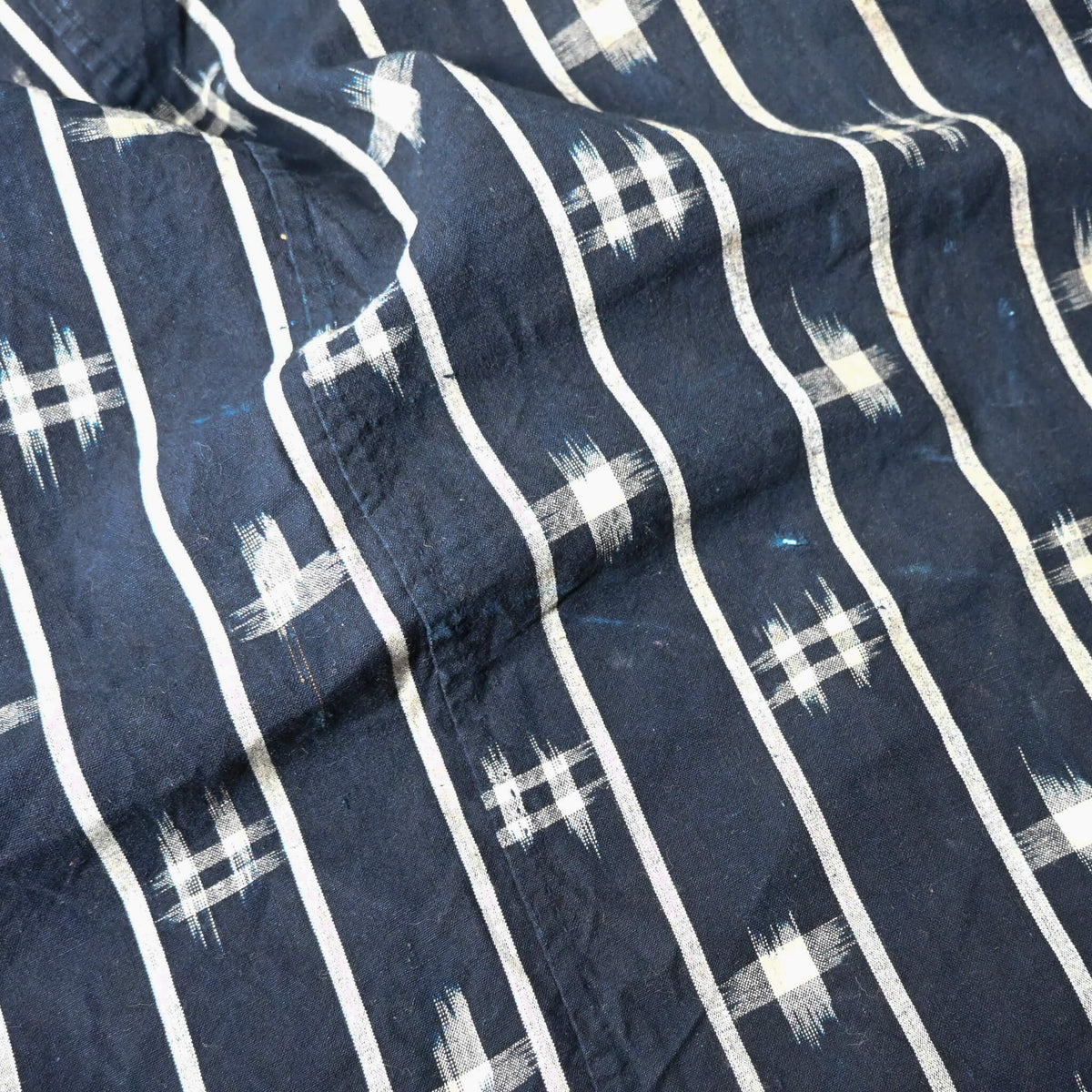 Close-up view of vintage three-panel indigo kasuri cotton furoshiki with hand stitched botanical motifs on the corner.