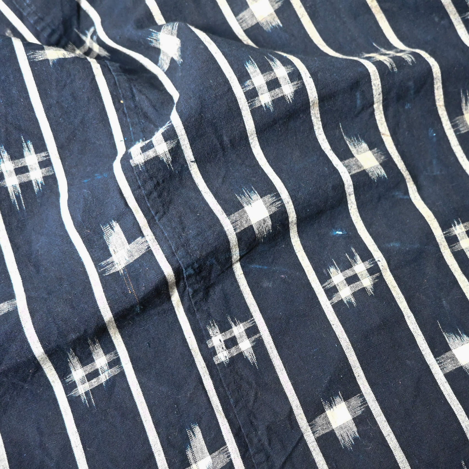 Close-up view of vintage three-panel indigo kasuri cotton furoshiki with hand stitched botanical motifs on the corner.