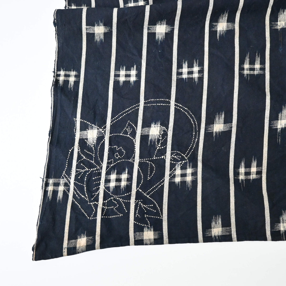 Detailed view of vintage three-panel indigo kasuri cotton furoshiki with hand stitched botanical motifs on the corner.