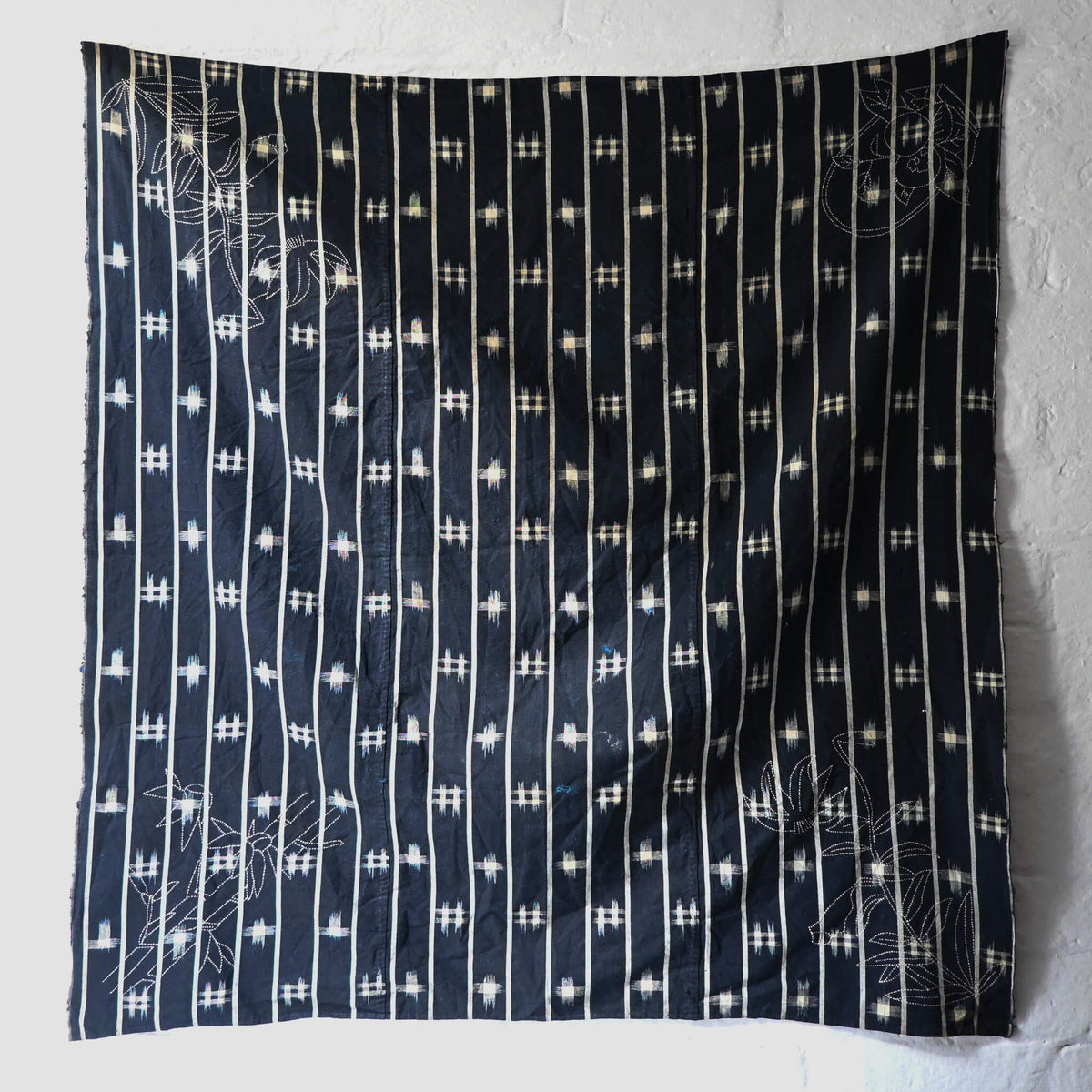 Full view of vintage three-panel indigo kasuri cotton furoshiki with hand stitched botanical motifs on the corner.