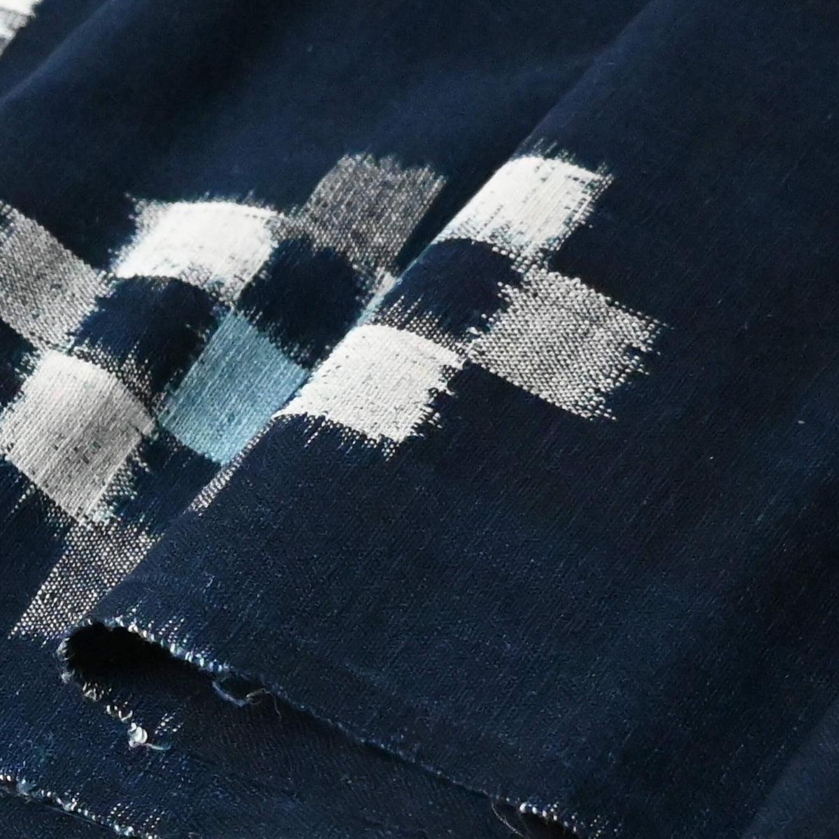 Close-up view of vintage Japanese indigo kasuri cotton panel from San'in region, a simple geometric pattern.