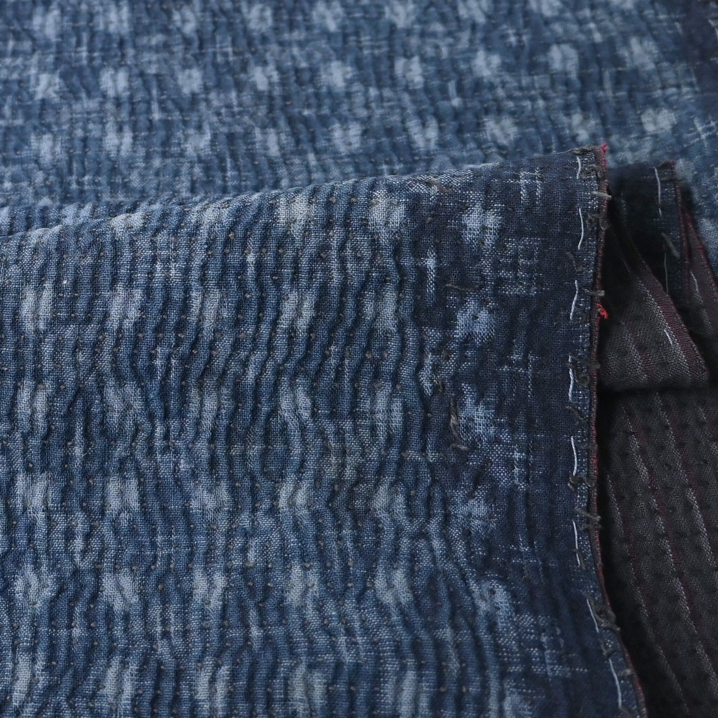 Close-up view of vintage indigo kasuri cotton with all-over sashiko stitch with texture.