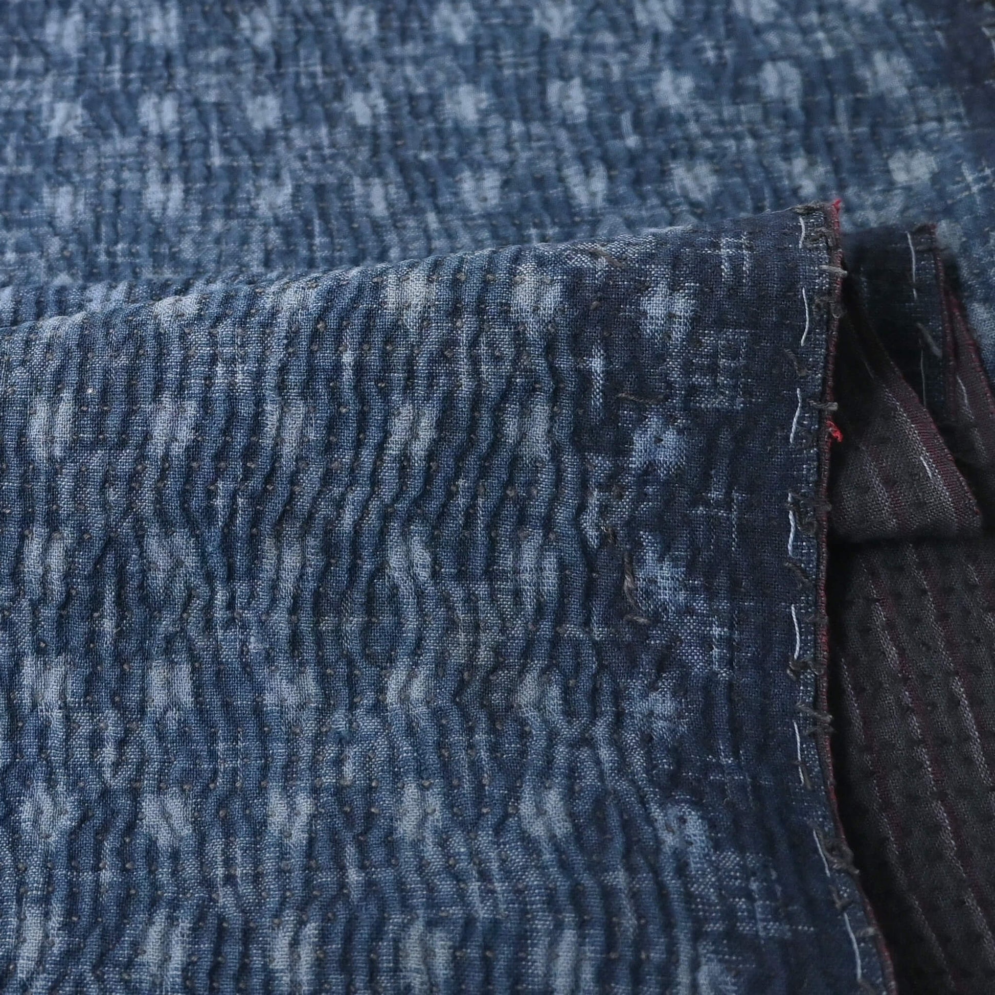 Close-up view of vintage indigo kasuri cotton with all-over sashiko stitch with texture.