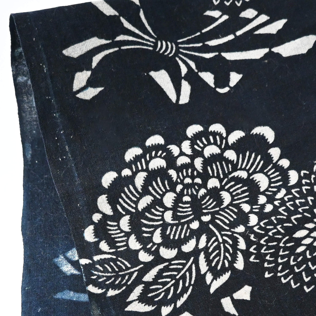Close-up view of vintage indigo katazome cotton fragment with peony, chrysanthemum and noshi paper motifs.