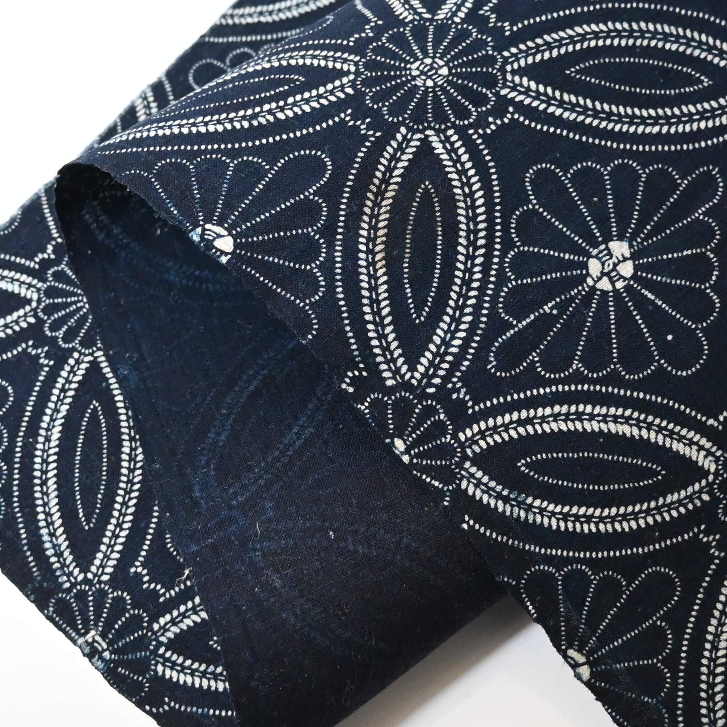 Close-up view of vintage indigo katazome cotton piece with Shippo-tsunagi with stylised chrysanthemum motif.