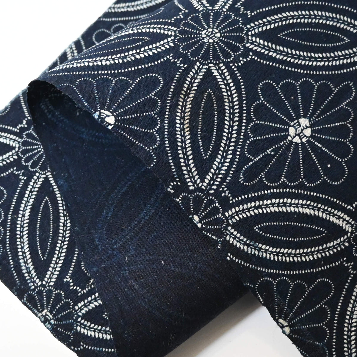 Close-up view of vintage indigo katazome cotton piece with Shippo-tsunagi with stylised chrysanthemum motif.