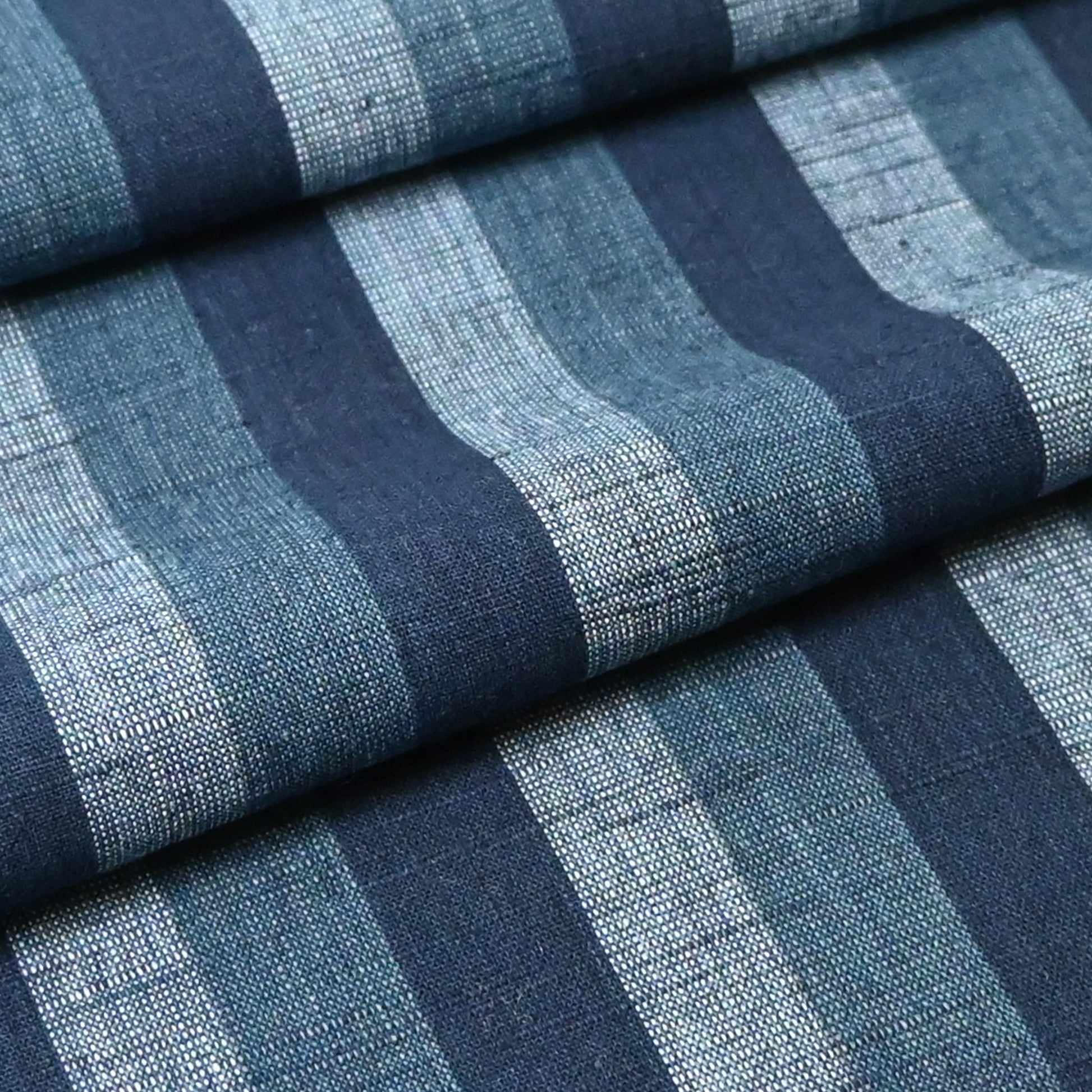 Close-up view of vintage Japanese indigo tsumugi stripe cotton fabric roll.