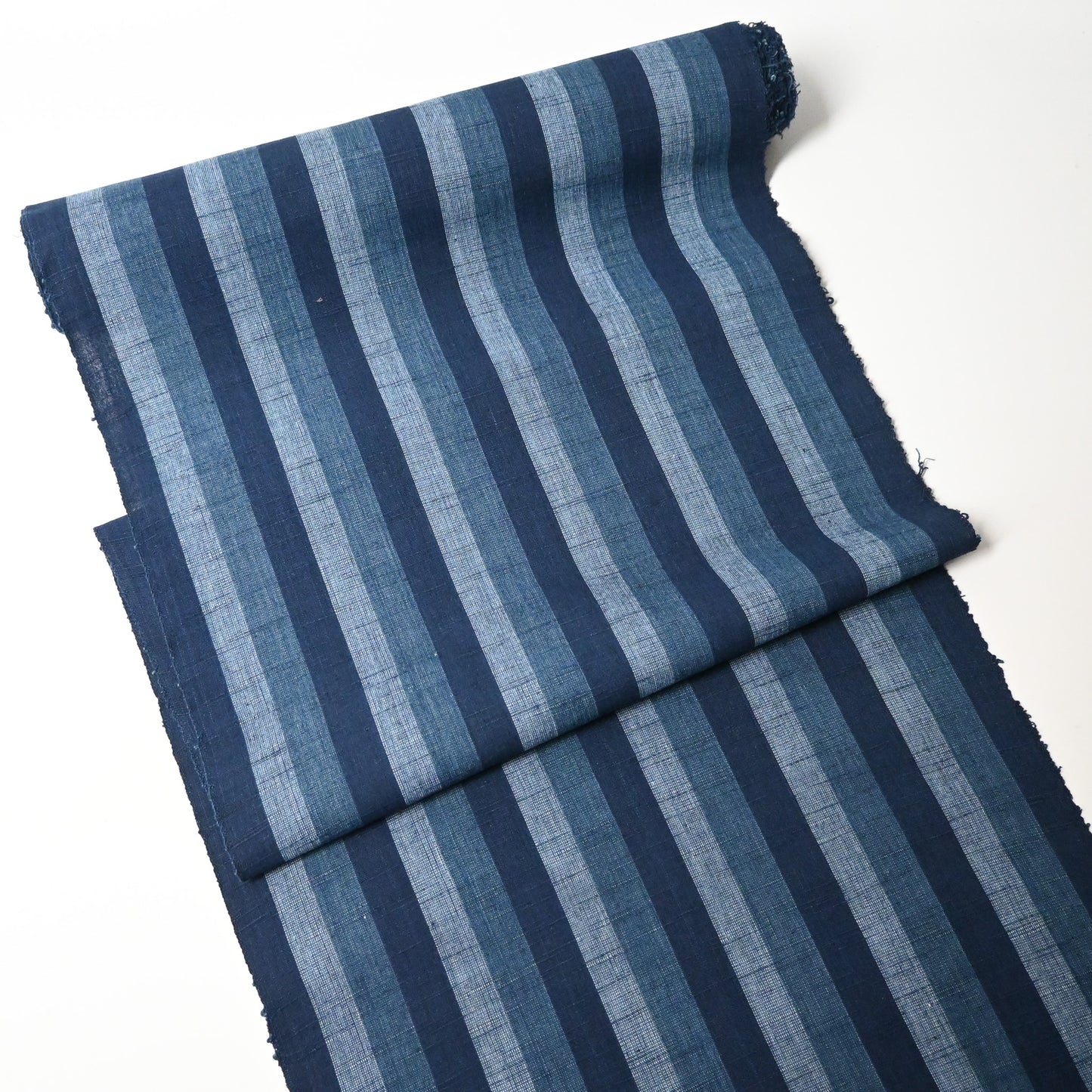 Full view of vintage Japanese indigo tsumugi stripe cotton fabric roll.