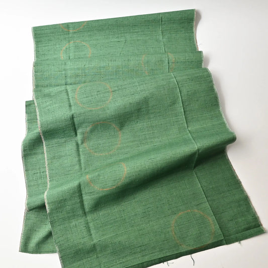Full view of vintage Jaapnese jade green tsumugi silk kimono fabric with subtle circular orange motif.