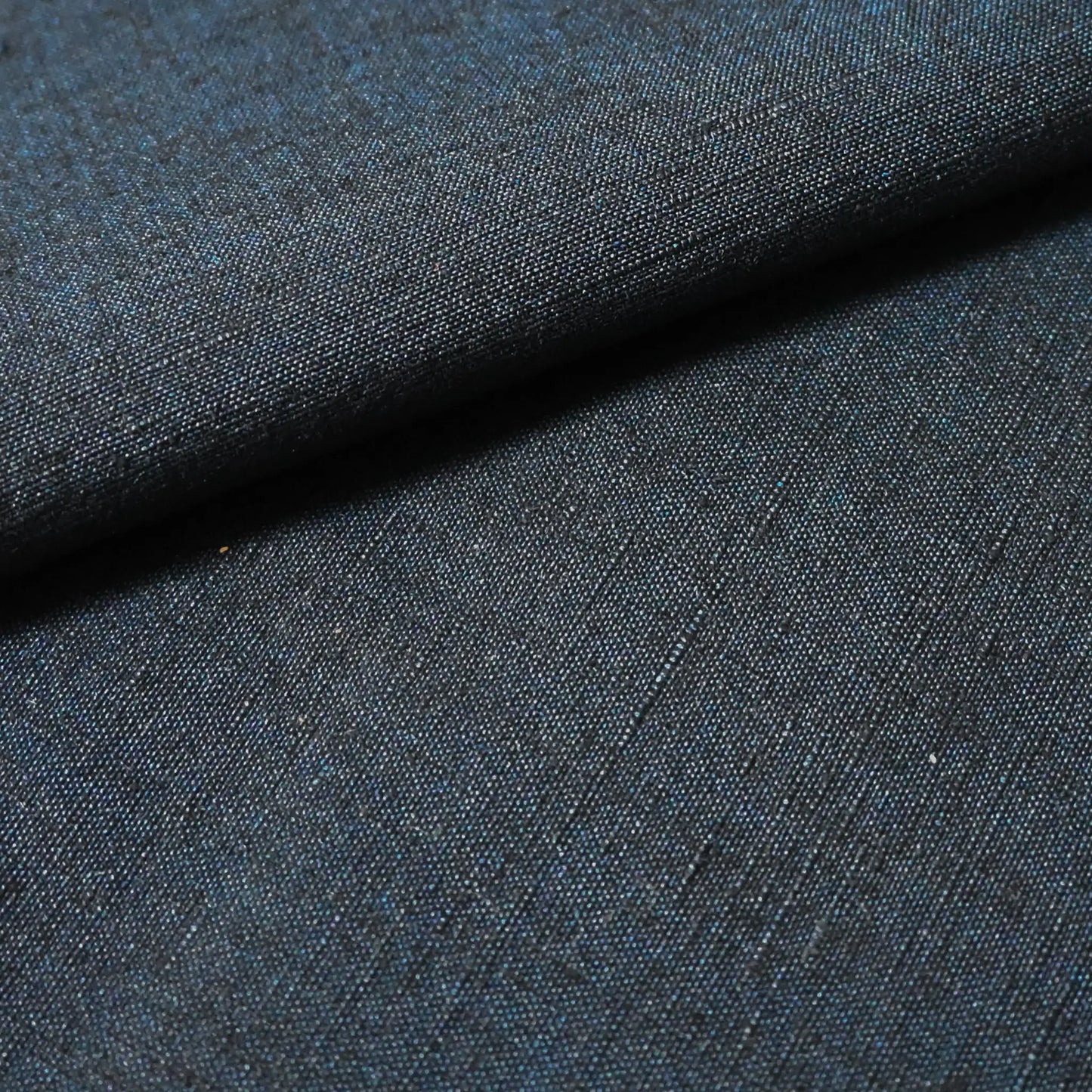 Close-up view of vintage dead stock men's tsumugi silk kimono fabric roll in dark sea tone.