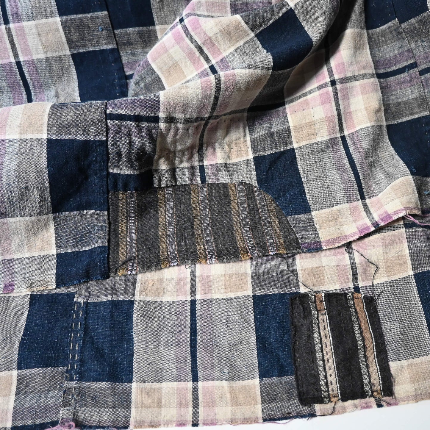 Detailed view of vintage Japanese indigo and soft pink check cotton futon cover with mended patches, boro textiles.