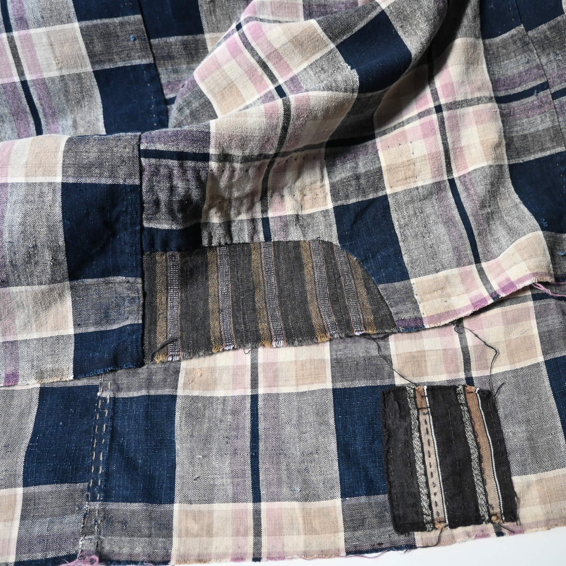 Detailed view of vintage Japanese indigo and soft pink check cotton futon cover with mended patches, boro textiles.