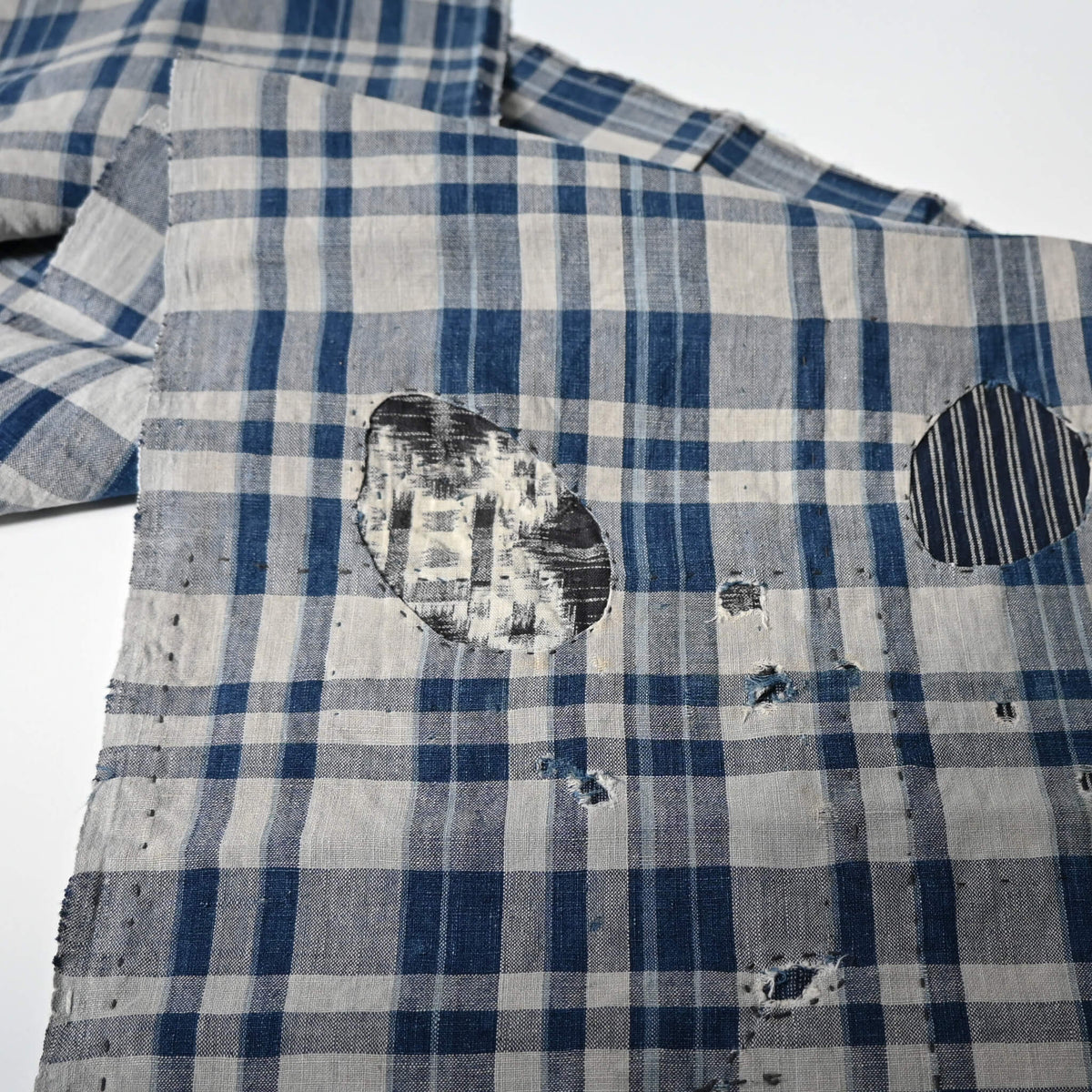 Vintage indigo check cotton with faded blue tones and aged texture, boro hand-stitched mend.